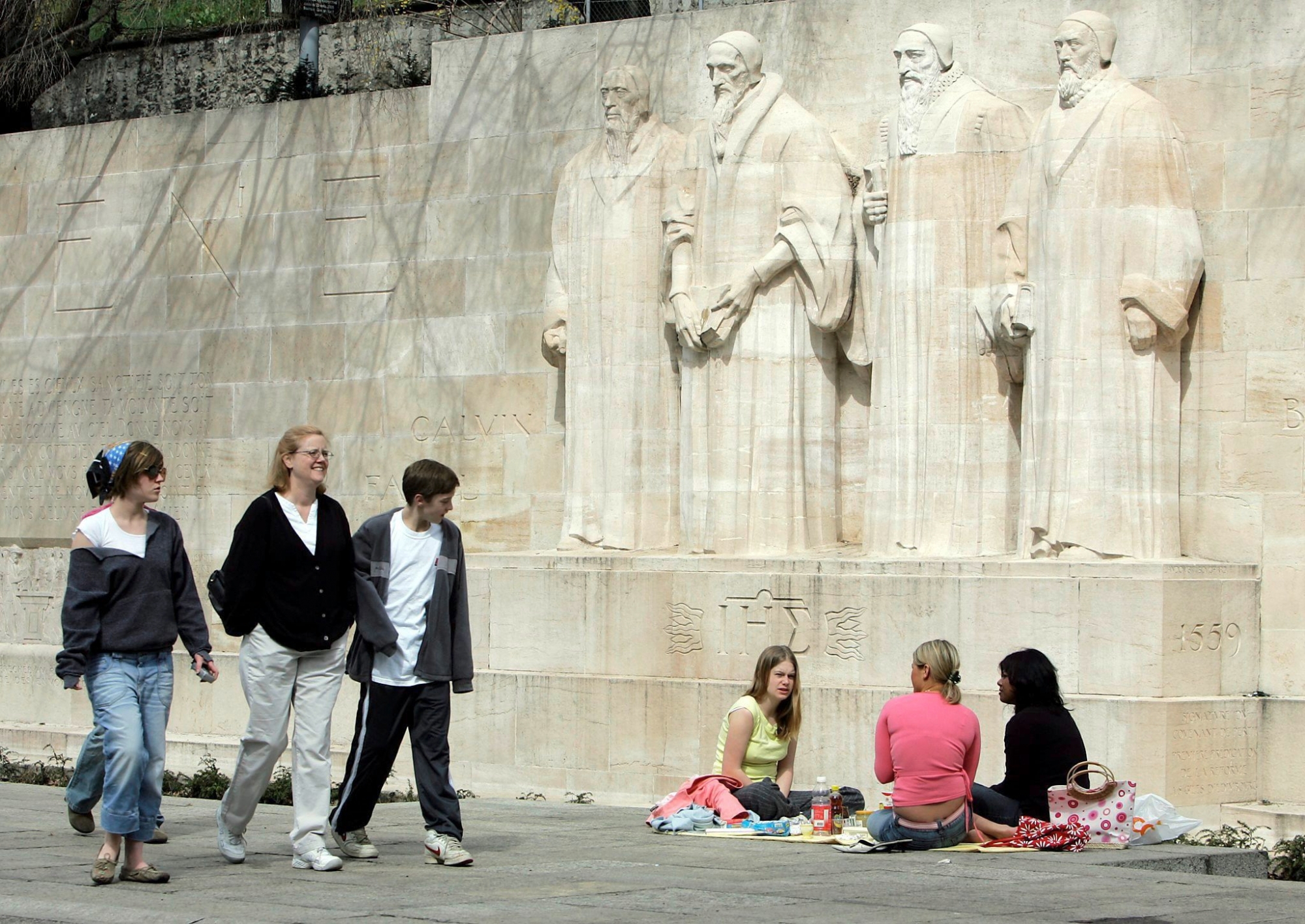 Des touristes pique-niquent tandis que díautres se promenent devant le mur des reformateurs a Geneve, ce lundi 28 mars 2005. (KEYSTONE/Martial Trezzini)
 SUISSE TOURISME MUR REFORMATEURS