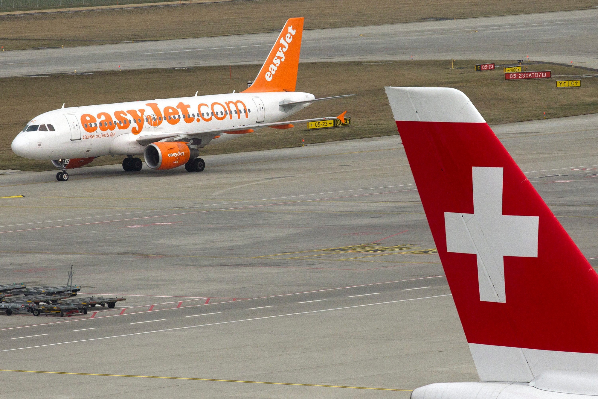 An easyJet Air Line aircraft runs on taxiway behind a Swiss International Air Lines aircraft at Geneva Airport, in Geneva, Switzerland, Tuesday, March 20, 2012. (KEYSTONE/Salvatore Di Nolfi) SWITZERLAND GENEVA AIRPORT