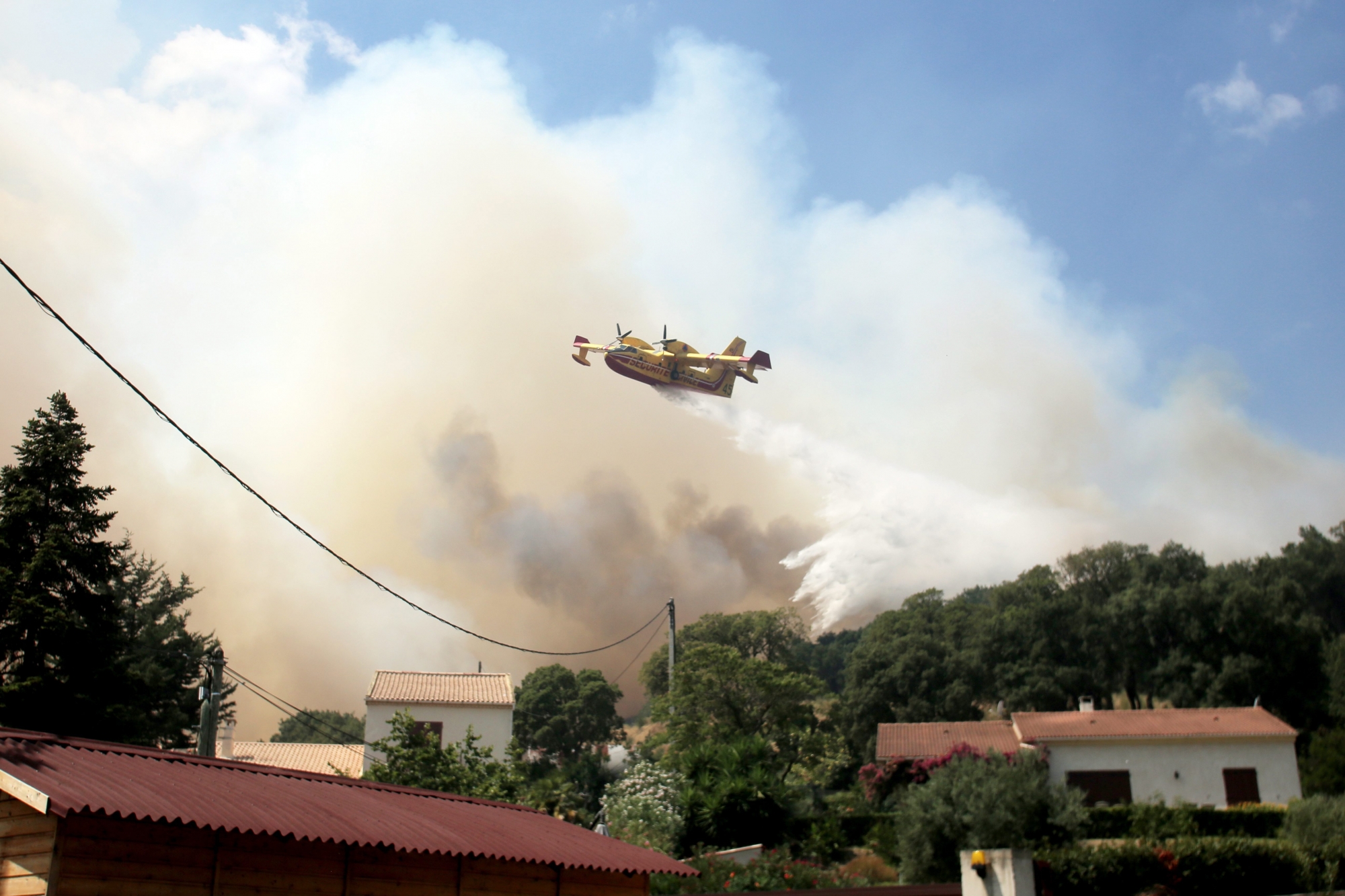 An anti-fire Canadair airplane drops water over a forest fire near the village of Ortale in Corsica, France, Tuesday, July 25, 2017. Hundreds of firefighters are battling blazes fanned by high winds in more than a dozen zones in the Riviera region of southern France. (AP Photo/Raphael Poletti) France Wildfires