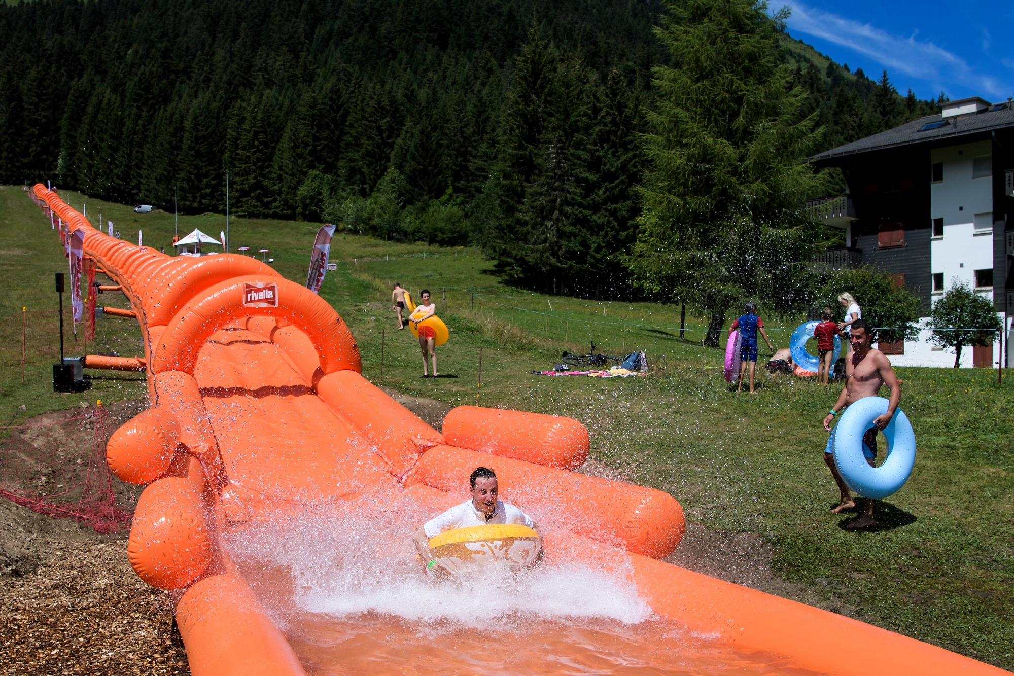 People enjoy a ride in a 315 meters long inflatable water slide toboggan named "Splash Your Mountain" during an event, in Morgins, Switzerland, Friday, July 28, 2017. (KEYSTONE/Jean-Christophe Bott) SWITZERLAND GIANT WATER SLIDE TOBOGGAN