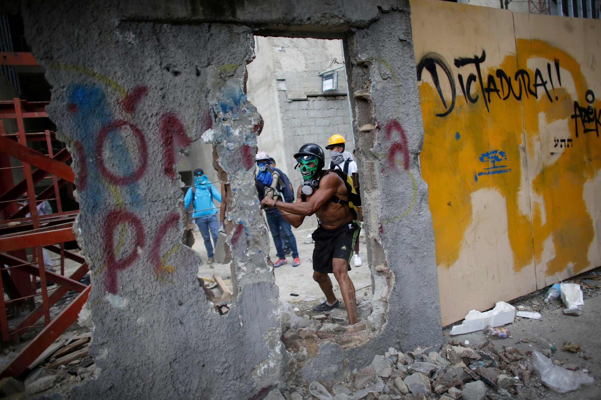 An anti-government demonstrator whacks a a wall to release pieces of concrete to throw at Venezuelan Bolivarian National Police, during a protest against the installation of a constitutional assembly in Caracas, Venezuela, Friday, Aug. 4, 2017. Defying criticism from Washington to the Vatican, Venezuela's ruling party on Friday installed a new super assembly that supporters promise will pacify the country and critics fear will be a tool for imposing dictatorship. (AP Photo/Ariana Cubillos) APTOPIX Venezuela Political Crisis