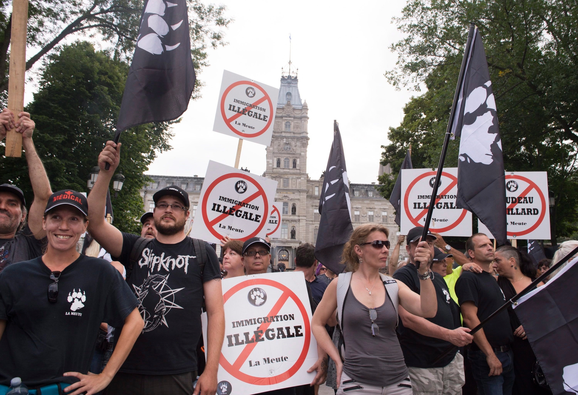Demonstrators of a right wing group, "La Meute" demonstrate in silence in front of the legislature, Sunday, Aug. 20, 2017 in Quebec City, Quebec. Tensions boiled over in Quebec City on Sunday, as police were pelted by beer bottles and smoke bombs set off in garbage cans in an ugly end to a weekend of pro and anti-immigrant rallies across the country. (Jacques Boissinot/The Canadian Press via AP) Canada Right Rally