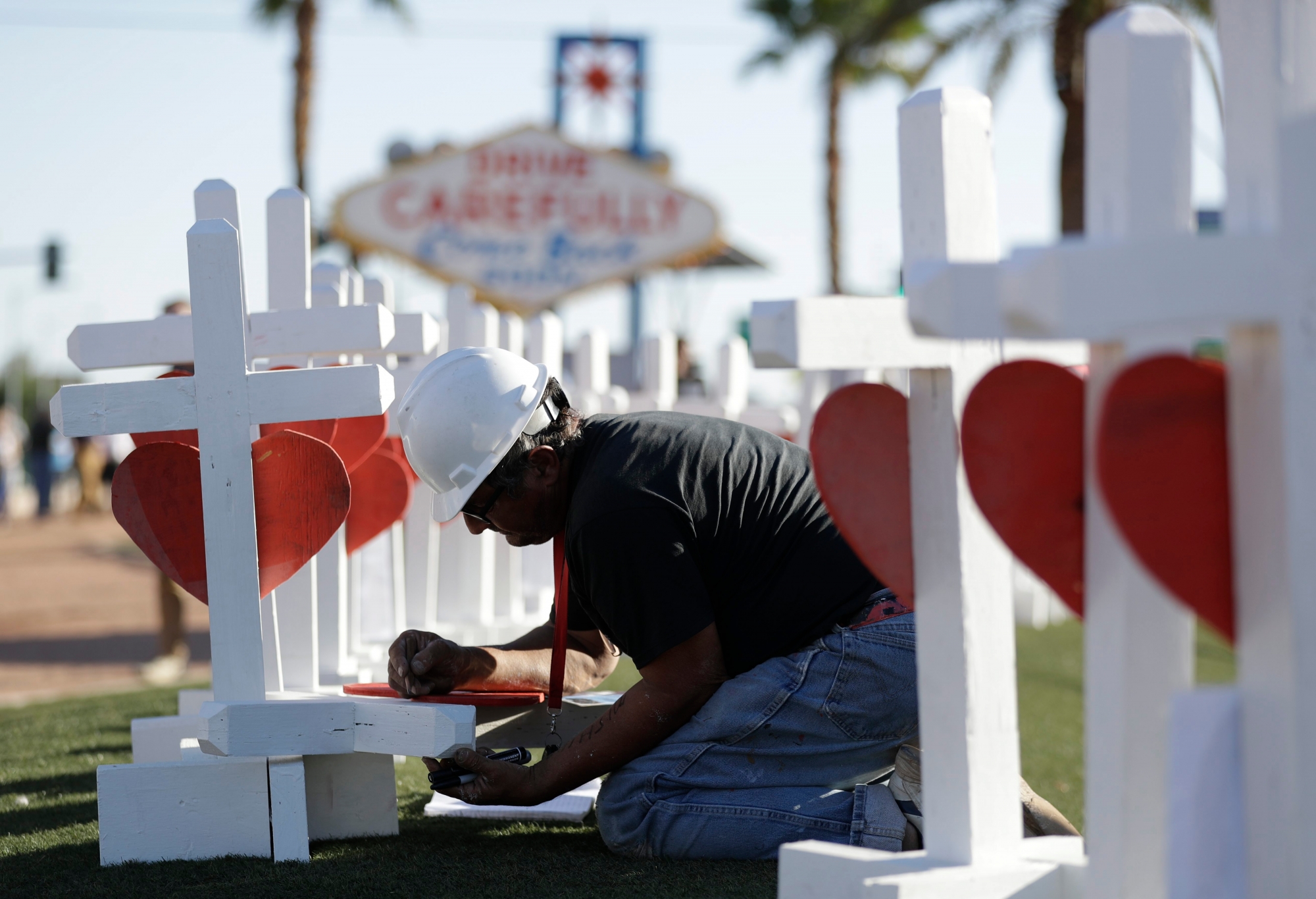 Greg Zanis writes the name of a victim of Sunday's mass shooting as he places crosses near the city's famous sign Thursday, Oct. 5, 2017, in Las Vegas. The crosses are in honor of those killed when Stephen Craig Paddock broke windows on the Mandalay Bay resort and casino and began firing with a cache of weapons onto a country music festival Sunday. Dozens of people were killed and hundreds were injured. (AP Photo/Gregory Bull) Las Vegas Shooting