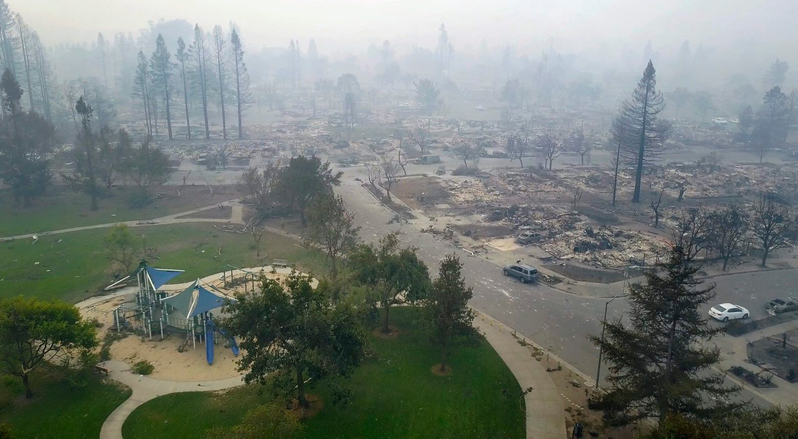 FILE - This Tuesday, Oct. 10, 2017, aerial image shows homes that were destroyed by a wildfire next to a playground in Santa Rosa, Calif. With winds expected to continue blowing smoke from the fires to populated areas this weekend, many schools decided to close Friday. (Nick Giblin/DroneBase via AP, File) California WIldfires Air Quality