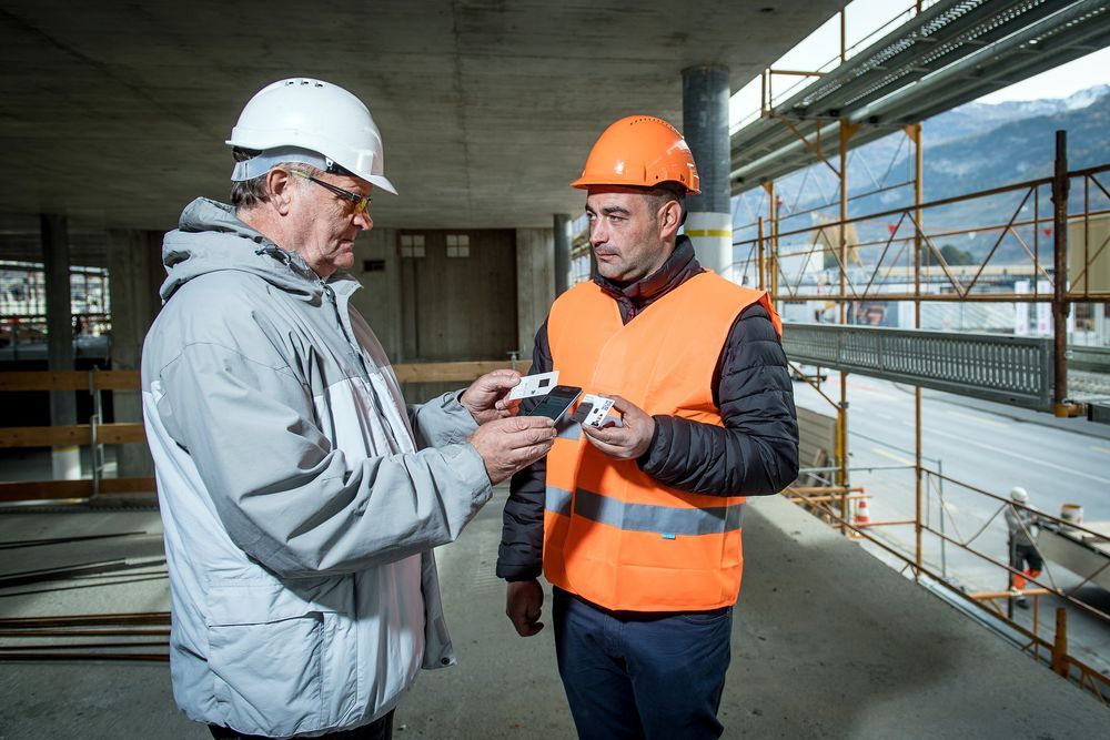 Le contrôleur Gérard-Philippe Meyer simule un contrôle de badge avec Marco, ouvrier sur un chantier.