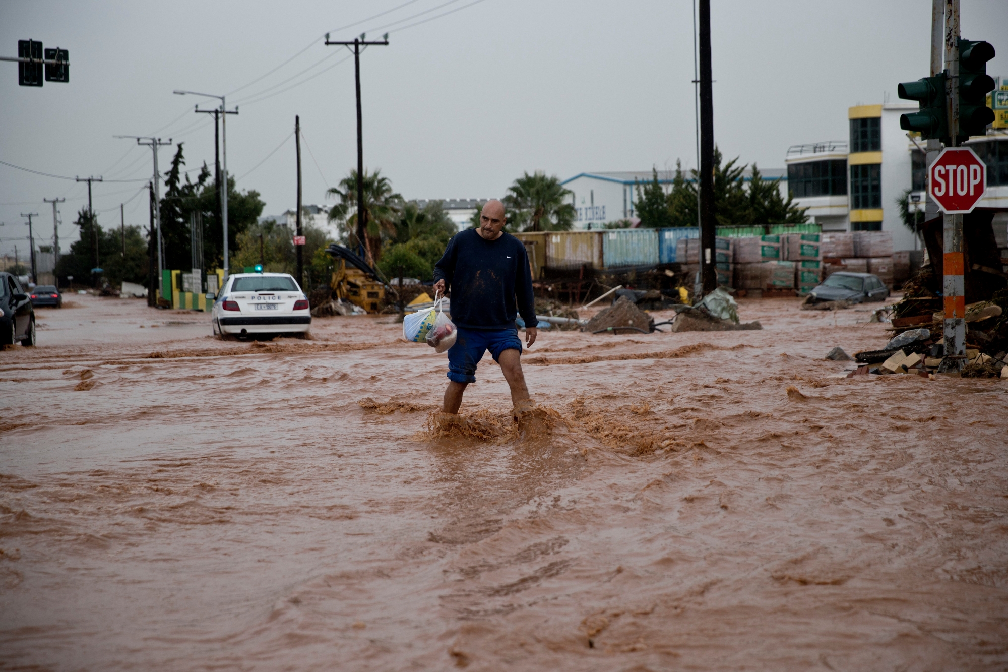 A man walks on a flooded street in the municipality of Mandra western Athens, on Wednesday, Nov. 15, 2017. Flash floods in the Greek capital's western outskirts Wednesday turned roads into raging torrents of mud and debris, killing at least nine people, inundating homes and businesses and knocking out a section of a highway. (AP Photo/Petros Giannakouris) APTOPIX Greece Storms