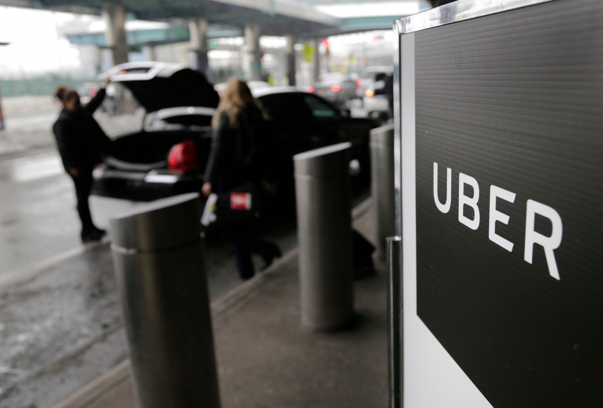 FILE - In this March 15, 2017, file photo, a sign marks a pick-up point for the Uber car service at LaGuardia Airport in New York. Uber is coming clean about its cover-up of a year-old hacking attack that stole personal information about more than 57 million of the beleaguered ride-hailing service's customers and drivers. The revelation Tuesday marks the latest stain on Uber's reputation. (AP Photo/Seth Wenig, File) Uber-Data Breach
