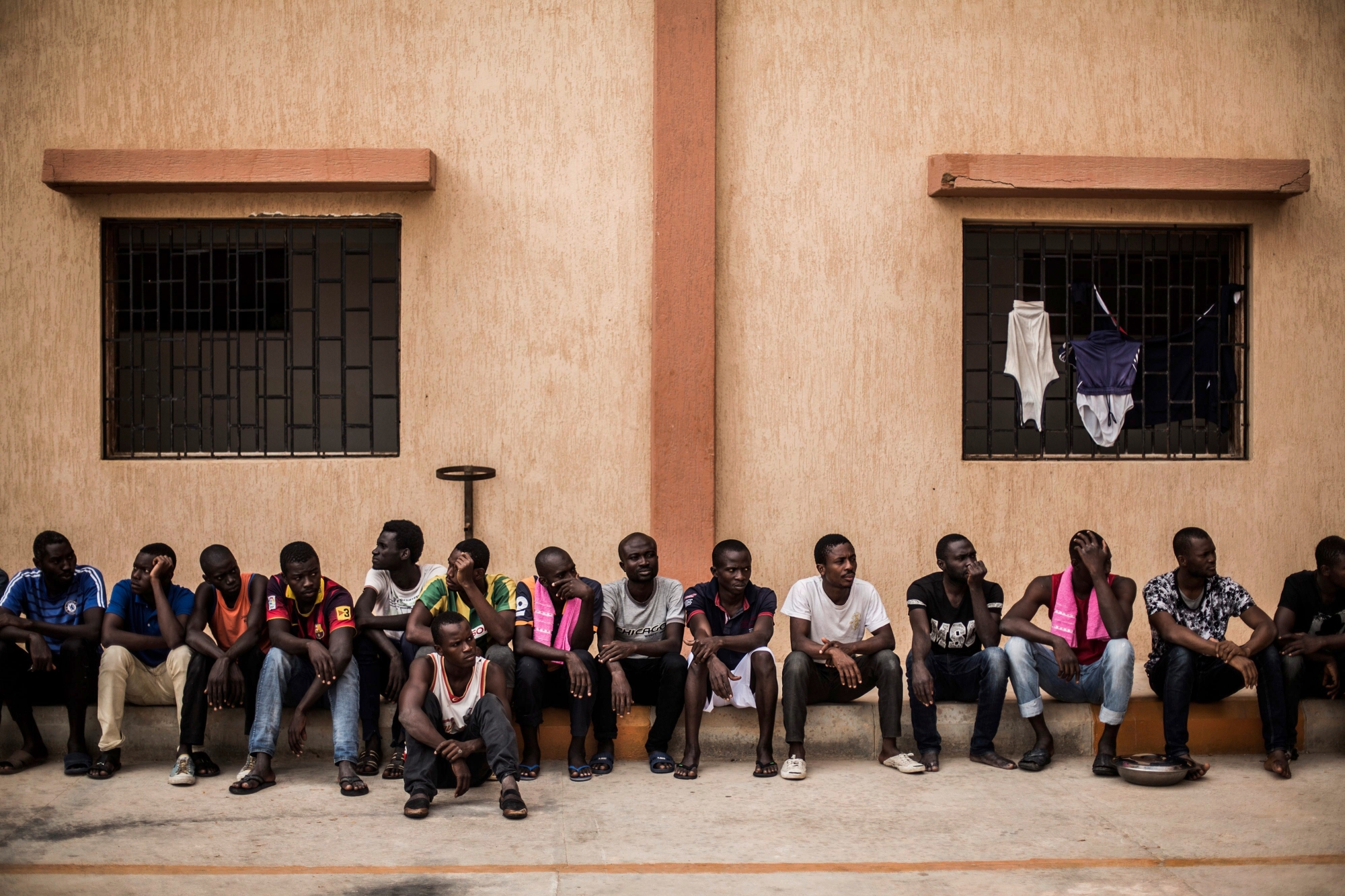Migrants wait to get in their barracks after having lunch in the courtyard of a detention center for migrants, in the village of Karareem, around 50 km from Misrata, Libya, Sunday, Sept. 25, 2016. Libya is an important transit and destination country for migrants who arrive seeking employment or a path to Europe. Some 700,000 to 1 million migrants are estimated to be in the country, according to International Organization for Migration. (AP Photo/Manu Brabo) XMB101