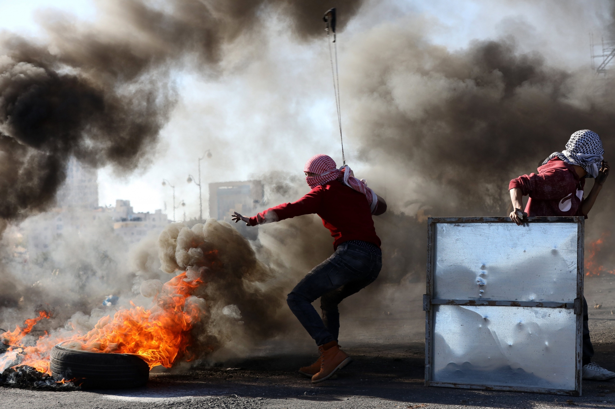 epa06377108 Palestinian protestors hurl stones at Israeli troops during clashes in the West Bank City of Ramallah, 08 December 2017. Palestinians announced general strike and a rage day to protest against US President Donald J. Trump declaration recognizing Jerusalem as the capital of the Israel.  EPA/ALAA BADARNEH MIDEAST PALESTINIAN ISRAEL CONFLICT