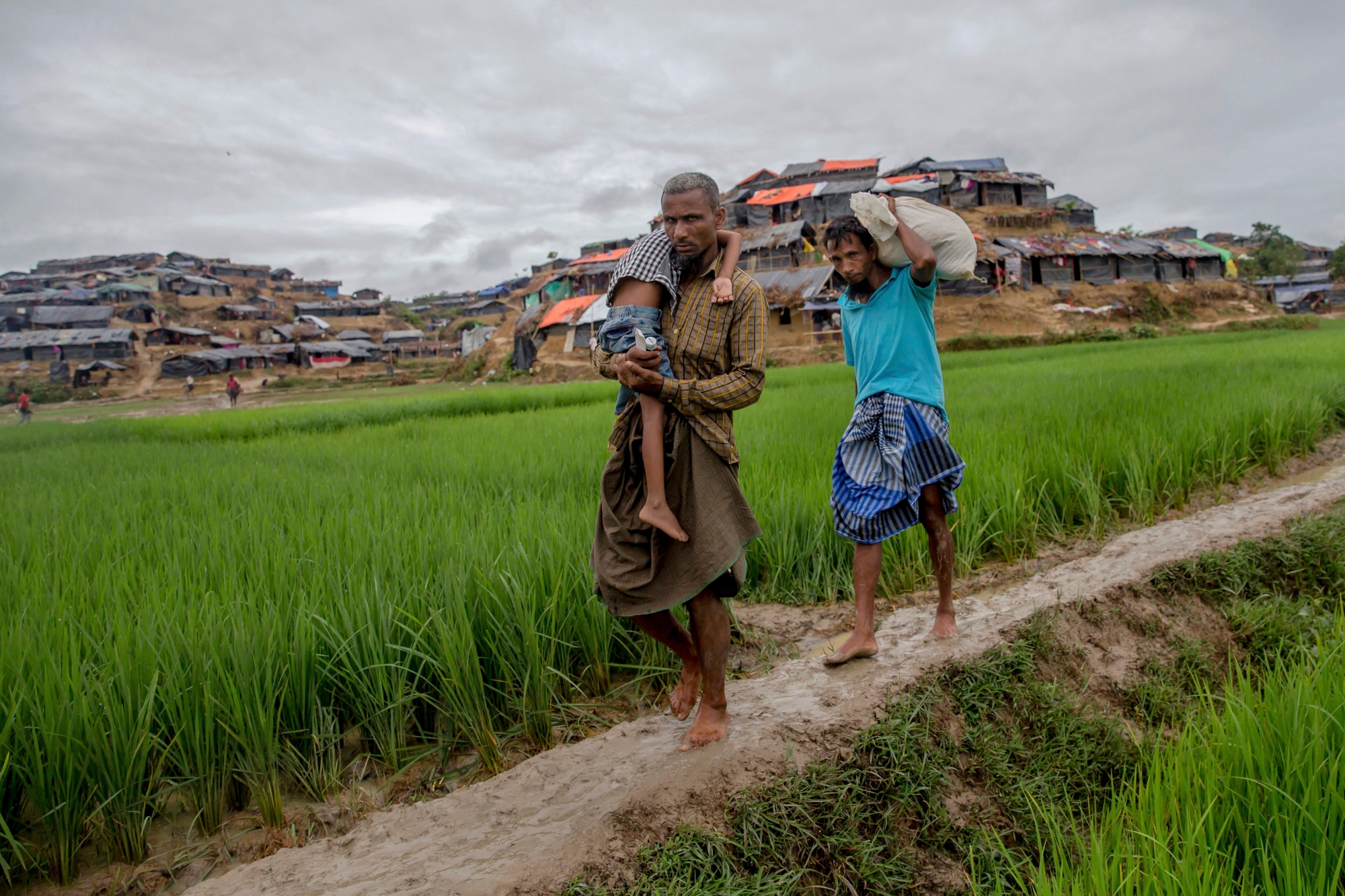 A Rohingya Muslim, who crossed over from Myanmar into Bangladesh, walks back to his shelter after taking his son to a doctor at a nearby clinic in Balukhali refugee camp, Bangladesh, Monday, Sept. 18, 2017. Bangladesh has been overwhelmed with more than 400,000 Rohingya who fled their homes in the last three weeks amid a crisis the U.N. describes as ethnic cleansing. Refugee camps were already beyond capacity and new arrivals were staying in schools or huddling in makeshift settlements with no toilets along roadsides and in open fields. (AP Photo/Dar Yasin) Bangladesh Myanmar Attacks