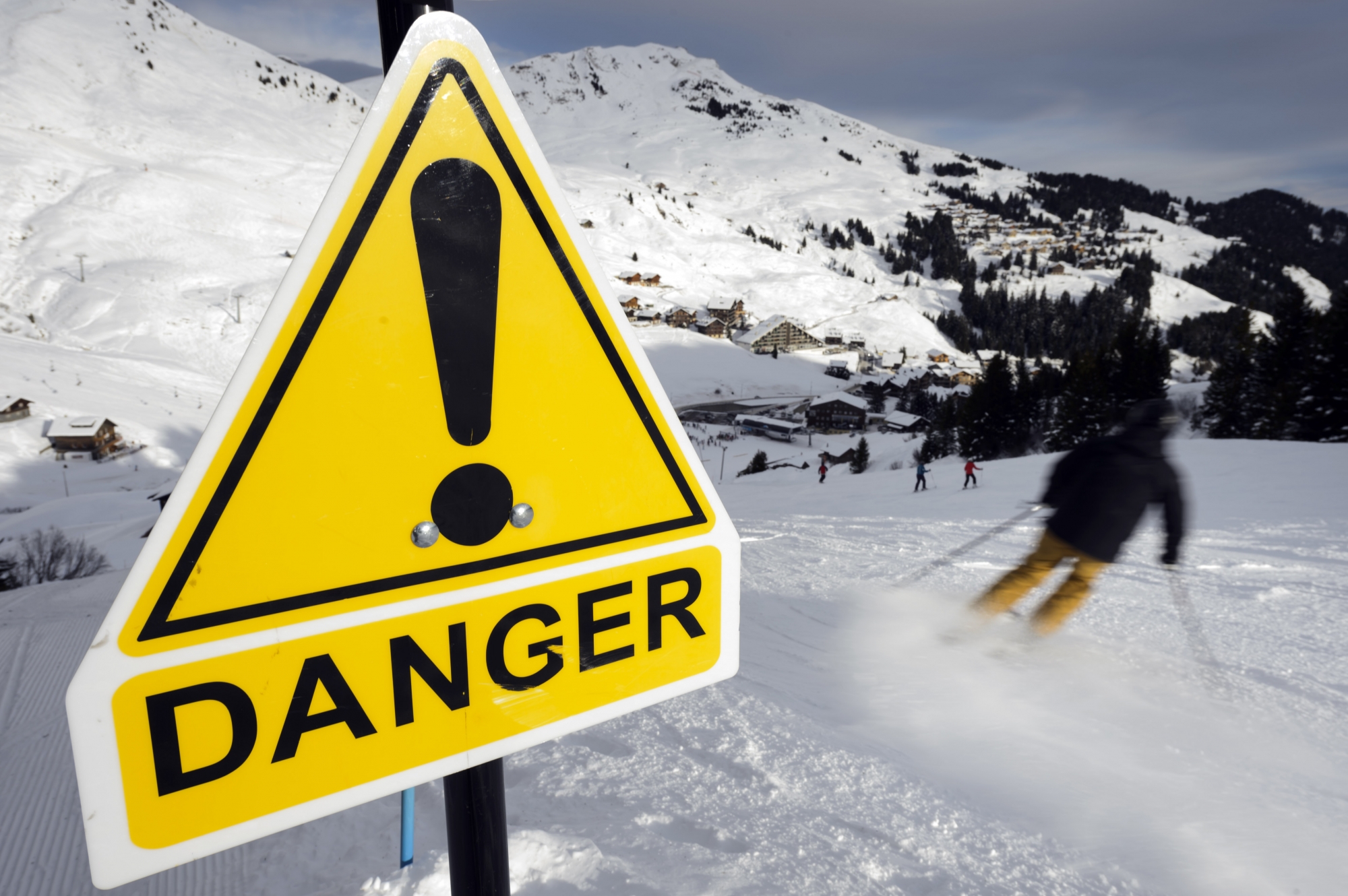 A Skier pass next to a warning sign on the skiing slopes, Saturday, December 28, 2013 at the Portes du Soleil area in the ski resort of Champery - Les Crosets, Switzerland. After the first snowfalls, the ski slopes have opened for the holiday season. (KEYSTONE/Laurent Gillieron)