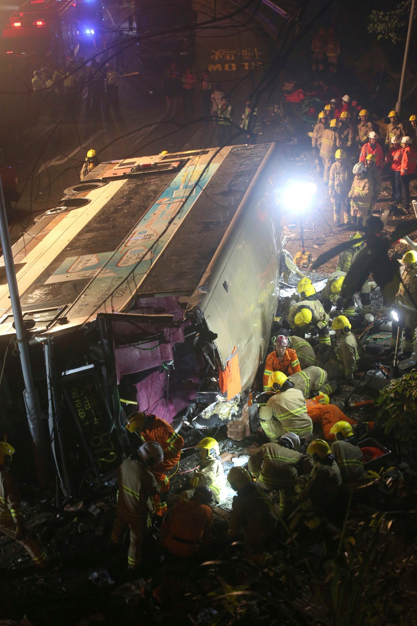 In this Feb. 10, 2018 photo, emergency workers prepare to rescue injured passengers from a double-decker lying on its side in Hong Kong. A double-decker bus lost control and crashed in a Hong Kong suburb on Saturday evening, killing a number of people and injuring dozens more, authorities in the southern Chinese city said. (AP Photo) Hong Kong Bus Crash