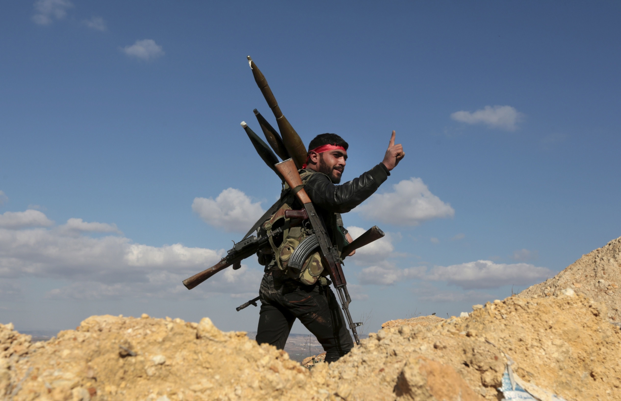 FILE - This Jan. 28, 2018 file photo, a pro-Turkey Syrian fighter waves on Bursayah hill, which separates the Kurdish-held enclave of Afrin from the Turkey-controlled town of Azaz, Syria. As Syrian troops and their allies push toward final victory and the battle against Islamic State militants draws to an end, new fronts are opening up, threatening an even broader confrontation. The U.S., Israel and Turkey all have deepened their involvement, seeking to protect their interests in the new Syria order. (AP Photo, File) SYRIA NEW FRONTS