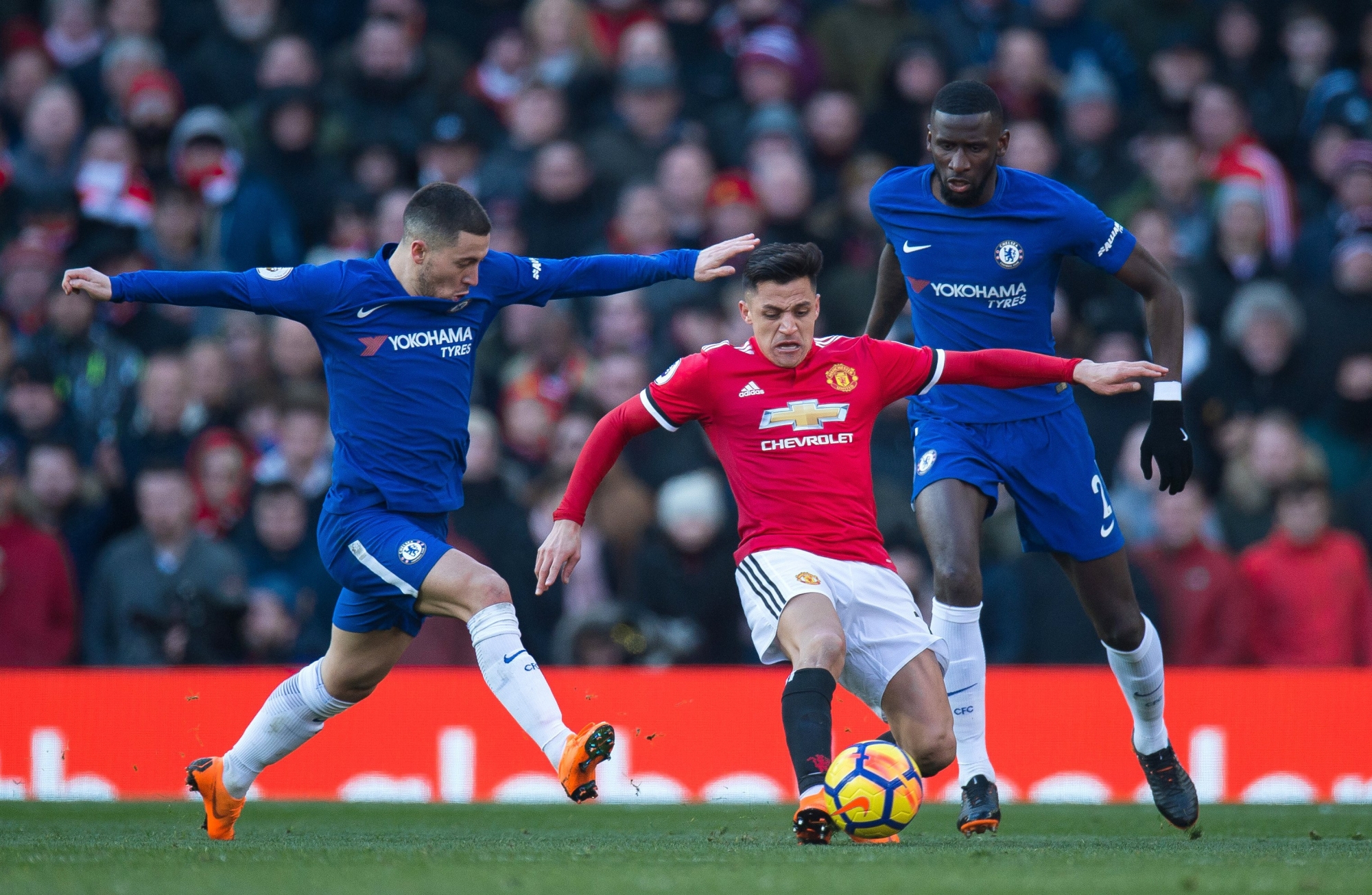 epa06564650 Chelsea's Antonio Ruediger (R) and Eden Hazard (L) in action with Manchester United's Alexis Sanchez (C) during the English Premier League soccer match between Manchester United and Chelsea FC held at Old Trafford, Manchester, Britain, 25 February 2018.  EPA/PETER POWELL EDITORIAL USE ONLY. No use with unauthorized audio, video, data, fixture lists, club/league logos or 'live' services. Online in-match use limited to 75 images, no video emulation. No use in betting, games or single club/league/player publications. BRITAIN SOCCER ENGLISH PREMIER LEAGUE