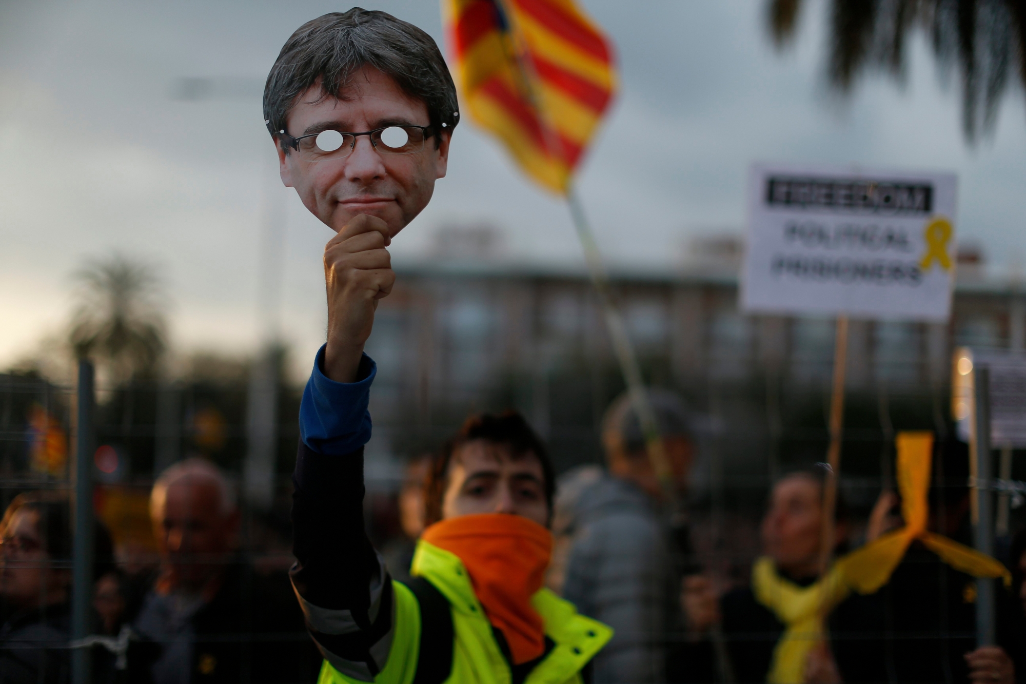 A pro independence demonstrator holds up a Carles Puigdemont mask during a protest of the detention of deposed leader of Catalonia's pro-independence party Carles Puigdemont in Barcelona, Spain, Sunday, March 25, 2018. Puigdemont was arrested Sunday by German police on an international warrant as he tried to enter the country from Denmark. (AP Photo/Manu Fernandez) Spain Catalonia