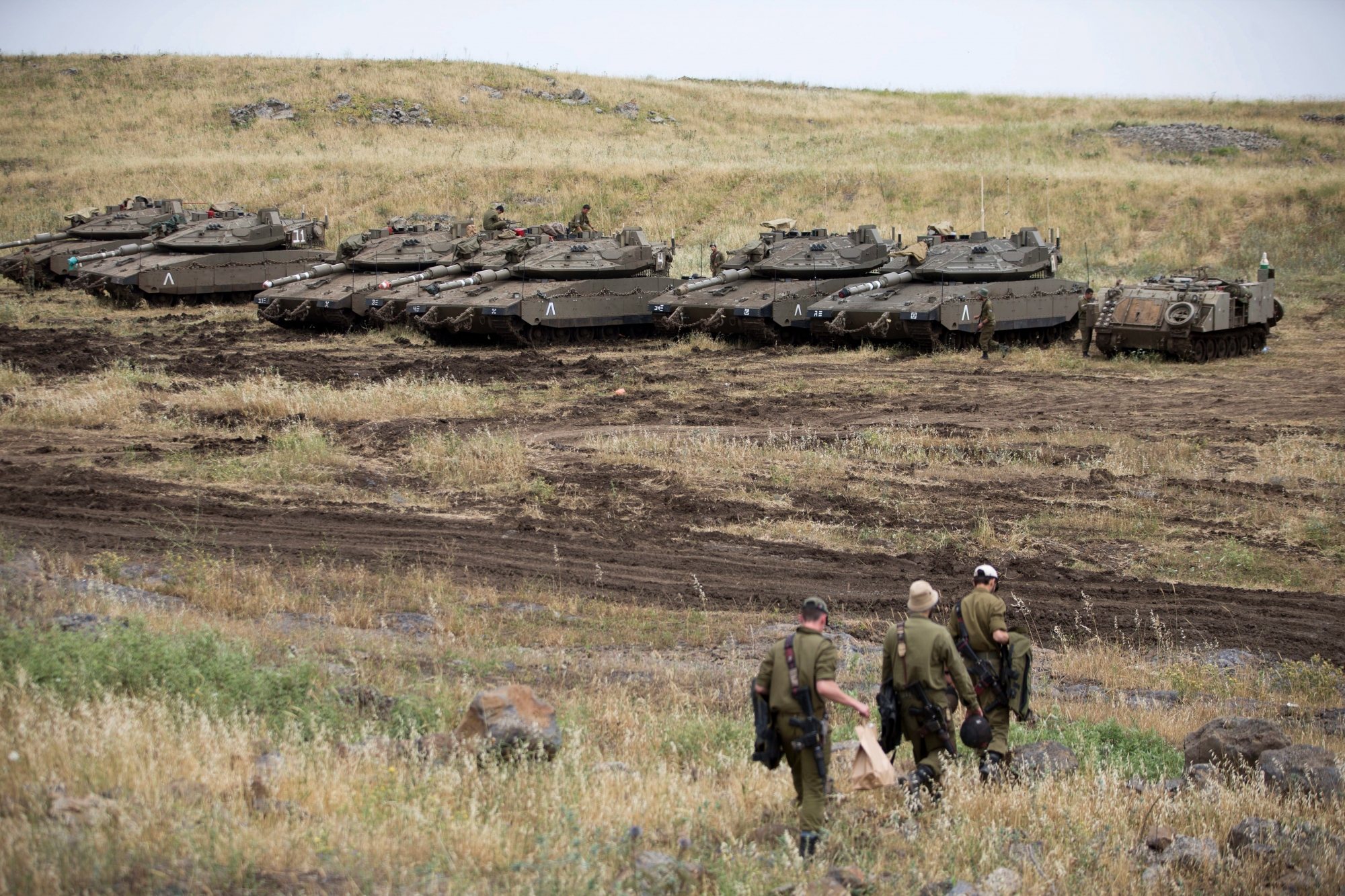 Israeli soldiers walk past tanks in the Israeli-controlled Golan Heights, near the border with Syria, Thursday, May 10, 2018. Israel says it struck dozens of Iranian targets in Syria overnight in response to a rocket barrage on Israeli positions in the Golan Heights. It was the biggest Israeli strike in Syria since the 1973 war. (AP Photo/Ariel Schalit) Israel Syria