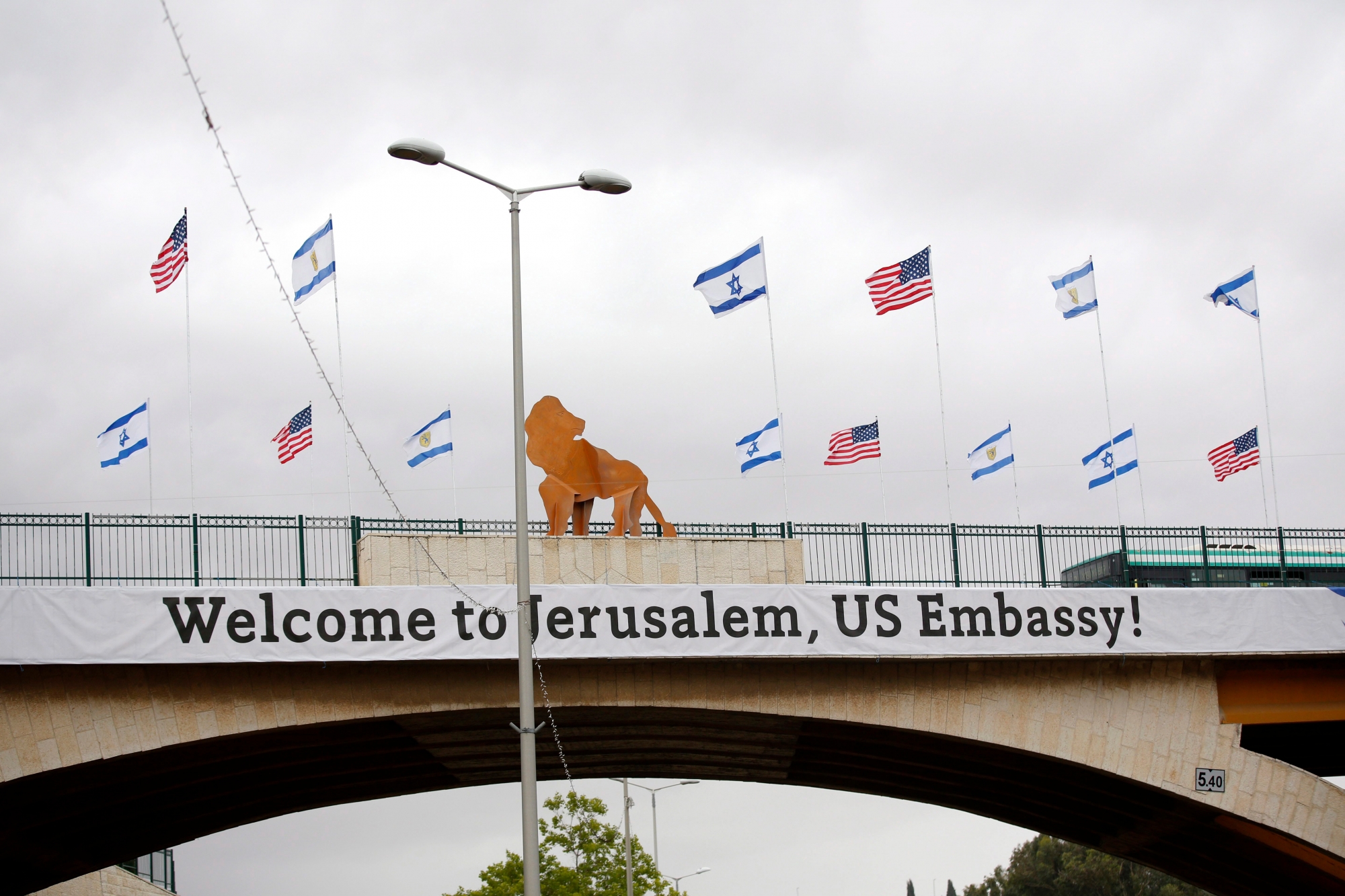 epa06732610 A sign and flags hung on a bridge nearby the US consulate that will act as the new US embassy in the Jewish neighborhood of Arnona, on the East-West Jerusalem line in Jerusalem, Israel, 13 May 2018. Trump's administration will officially transfer the ambassador's offices to the consulate building and temporarily use it as the new US Embassy in Jerusalem as of 14 May 2018. Trump in December 2017 recognized Jerusalem as Israel's capital and announced an embassy move from Tel Aviv, prompting protests in the occupied Palestinian territories and several Muslim-majority countries.  EPA/ABIR SULTAN MIDEAST ISRAEL USA EMBASSY