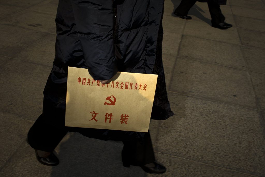 A delegate holds an envelop printed with the Communist Party of China emblem and Chinese characters, that read "Chinese Communist Party 18th National Congress documents," as she leaves the Great Hall of the People after the opening session of the 18th Communist Party Congress in Beijing, China, Thursday, Nov. 8, 2012. China's ruling Communist Party opened a congress Thursday to usher in a new group of younger leaders faced with the challenging tasks of righting a flagging economy and meeting public calls for better government. (AP Photo/Alexander F. Yuan)