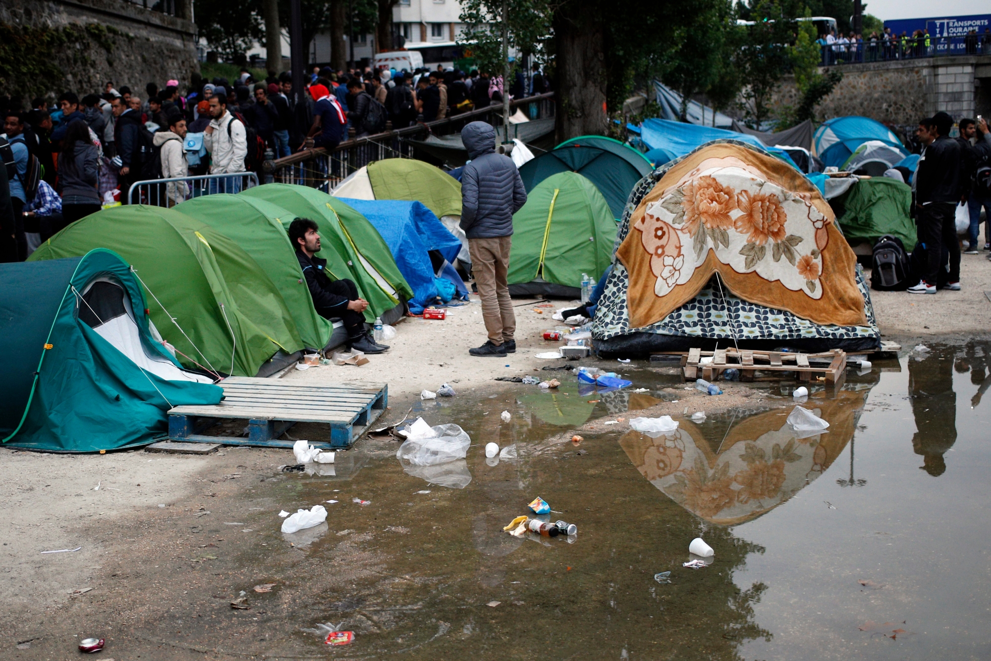 Migrants wait to leave during a clearing out of a makeshift migrant camp along side of the canal Saint Martin, in central Paris, France, Monday, June 4, 2018. French police have evacuated around 500 migrants, mostly Afghans but some Africans from a makeshift tent encampment. (AP Photo/Francois Mori) France Migrants