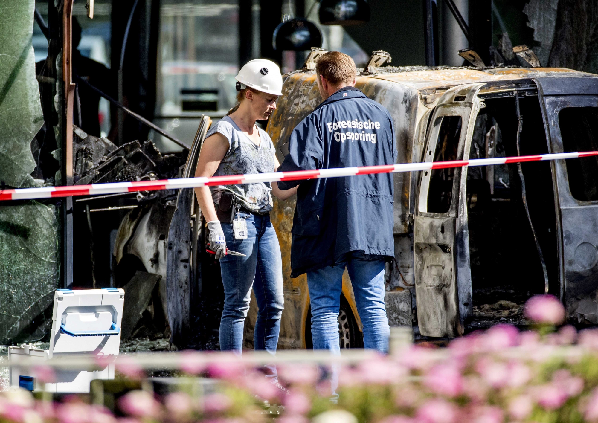 epa06840850 Police officers examine the scene around a van that crashed through the front door of the building that houses newspaper De Telegraaf on Basisweg in Amsterdam, The Netherlands, 26 June 2018. The vehicle went up in flames, causing a large amount of damage to the building. No one was injured in the accident.  EPA/KOEN VAN WEEL NETHERLANDS TRANSPORT ACCIDENT