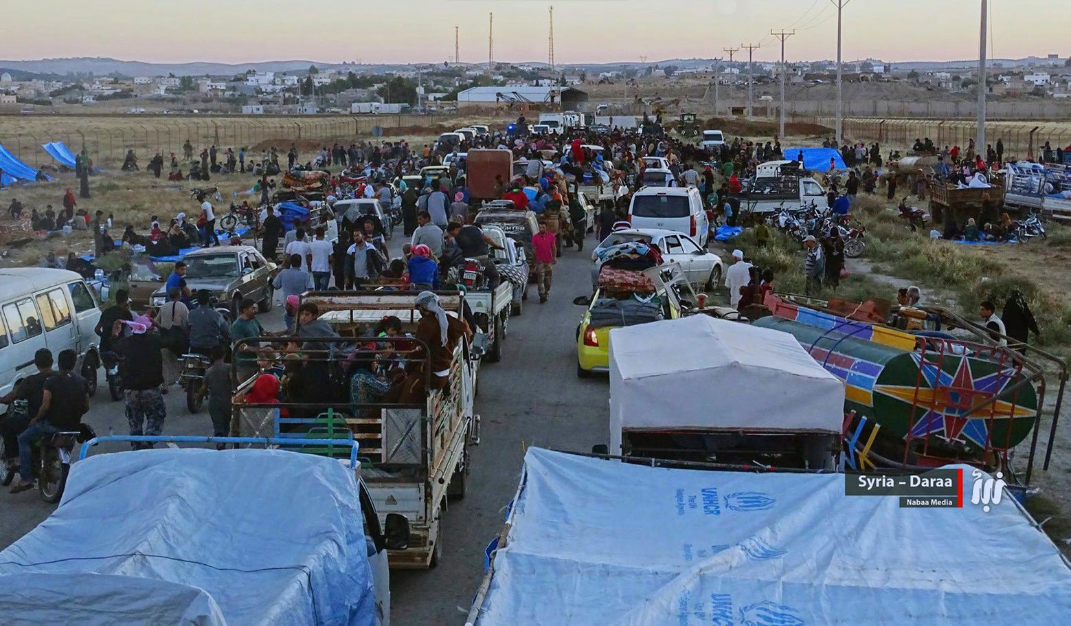 This Saturday, June 30, 2018, photo provided by Nabaa Media, a Syrian opposition media outlet, shows people in their vehicles who fled from Daraa, gathering near the Syria-Jordan border. Jordan's foreign minister said on Monday that he will hold talks with his Russian counterpart over the conflict in Syria, where the latest government offensive in the country's south has displaced 270,000 people, according to a U.N. officials. (Nabaa Media, via AP) Syria