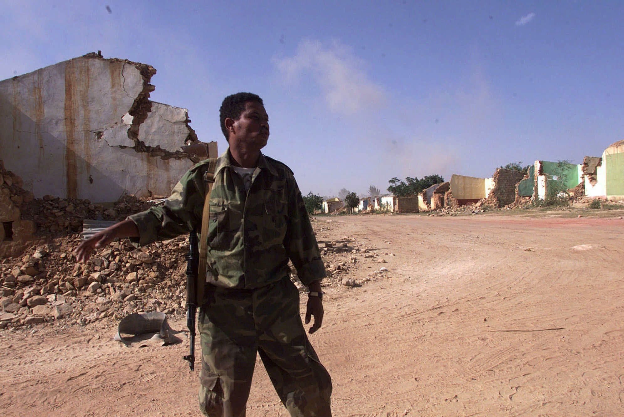 An Eritrean soldier tell his comrades to take shelter against shelling in the town of Zalambessa, 120 kms south of Asmara, Wednesday, May 24, 2000. The town has been thoroughly destroyed by the Ethiopian army some months ago. The town, in the disputed area between Eritrea and Ethiopia is under Eritrean control. Wednesday is Independence Day in Eritrea, gained nine years ago from Ethiopia. (KEYSTONE/AP/Jean-Marc Bouju) ERITREA HORN OF AFRICA WAR