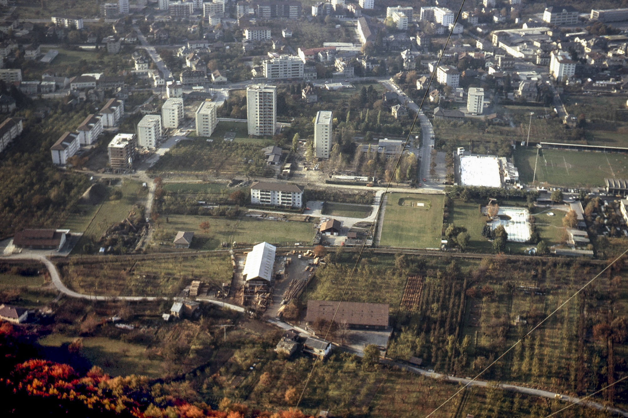 La ville de Martigny en 1973. Quelques immeubles sont sortis de terre, mais le site où sera construite la Fondation Pierre Gianadda, à gauche sur cette photo, autour du Vieil Arsenal, est encore occupé par des vergers d'arbres fruitiers.