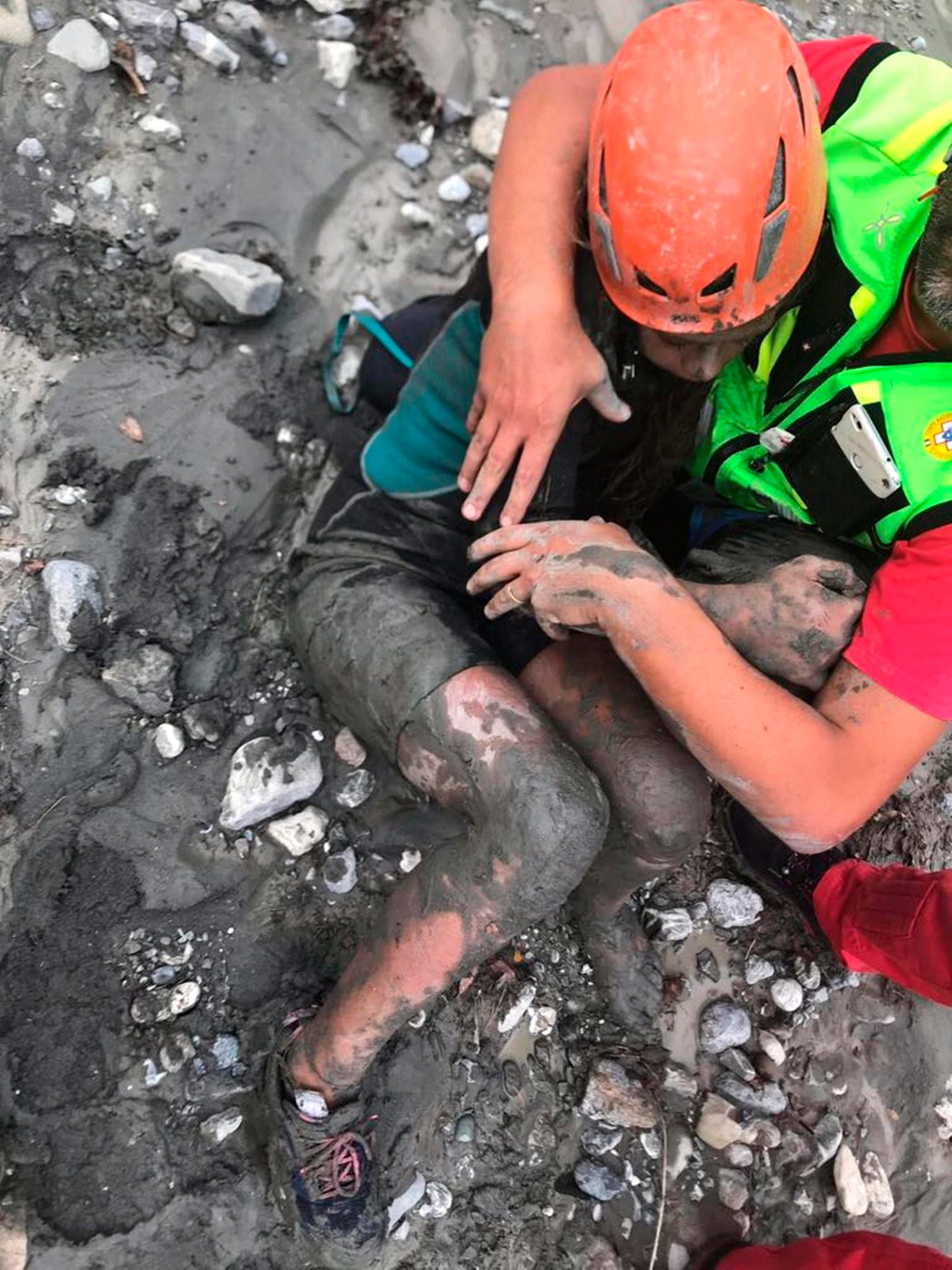 A girl is assisted by a member of the National Alpine and Caving Rescue Squad (CNSAS), in the Raganello Gorge in Civita, Italy, Tuesday Aug. 21, 2018.  Italy's civil protection agency says the death toll in a flash flood that swept away hikers in a narrow gorge in the southern region of Calabria has risen to 10. At least three others are missing, too. (ANSA via AP) Italy Flood