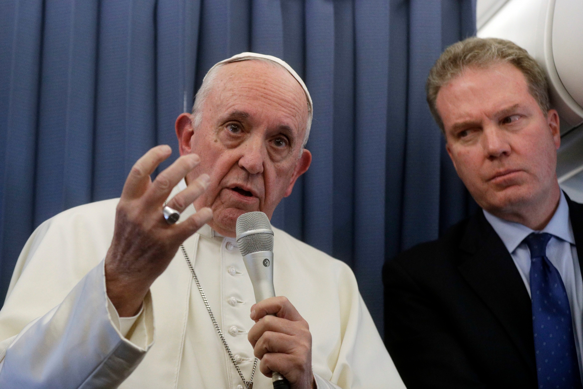 Pope Francis, flanked by Vatican spokesperson Greg Burke, listens to a journalist's question during a press conference aboard of the flight to Rome at the end of his two-day visit to Ireland, Sunday, Aug. 26, 2018. (AP Photo/Gregorio Borgia, Pool) Ireland Pope