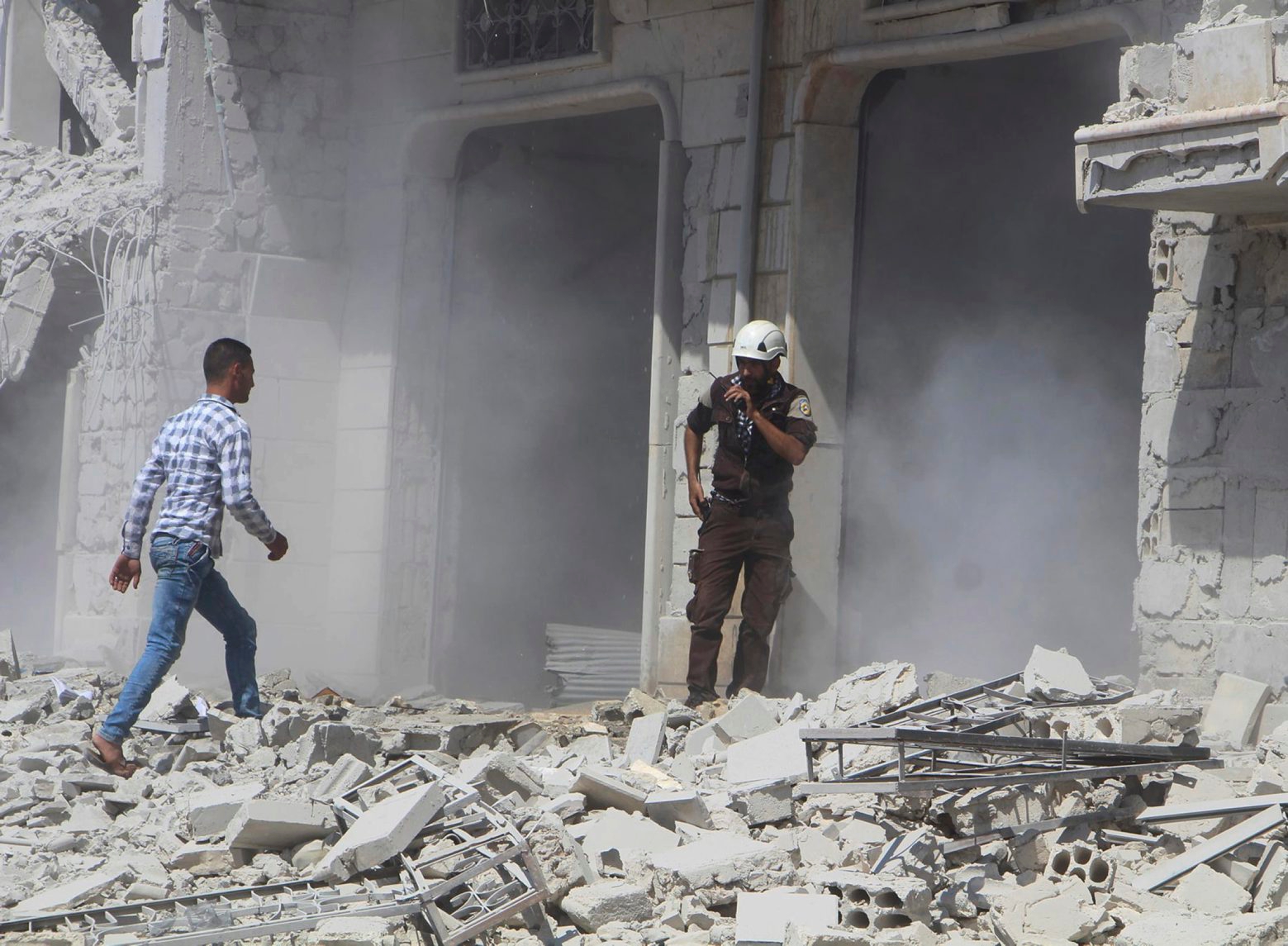 This photo provided by the Syrian Civil Defense group known as the White Helmets, shows a civil defense worker speaking on his radio next to a building that was attacked by a Syrian government airstrike, in Hobeit village, near Idlib, Syria, Sunday, Sept. 9, 2018. The White Helmets and a conflict monitoring group said Sunday that government and Russian forces have resumed their bombing of the opposition's last stretch of territory in the country, killing an infant girl and damaging a hospital. (Syrian Civil Defense White Helmets via AP) Syria