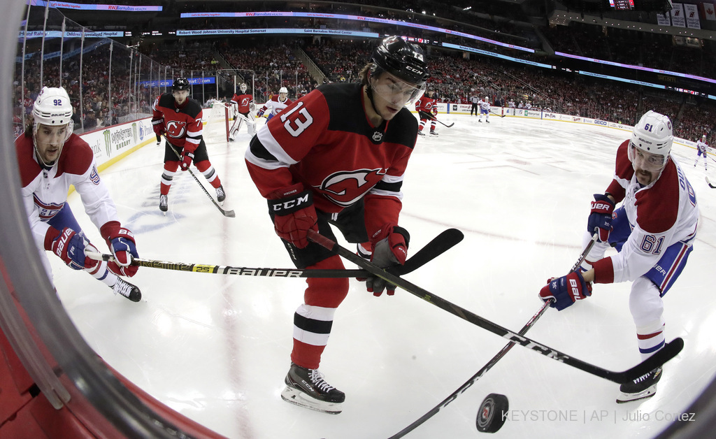 Nico Hischier disputant le puck avec Jonathan Drouin et le défenseur Xavier Ouellet.