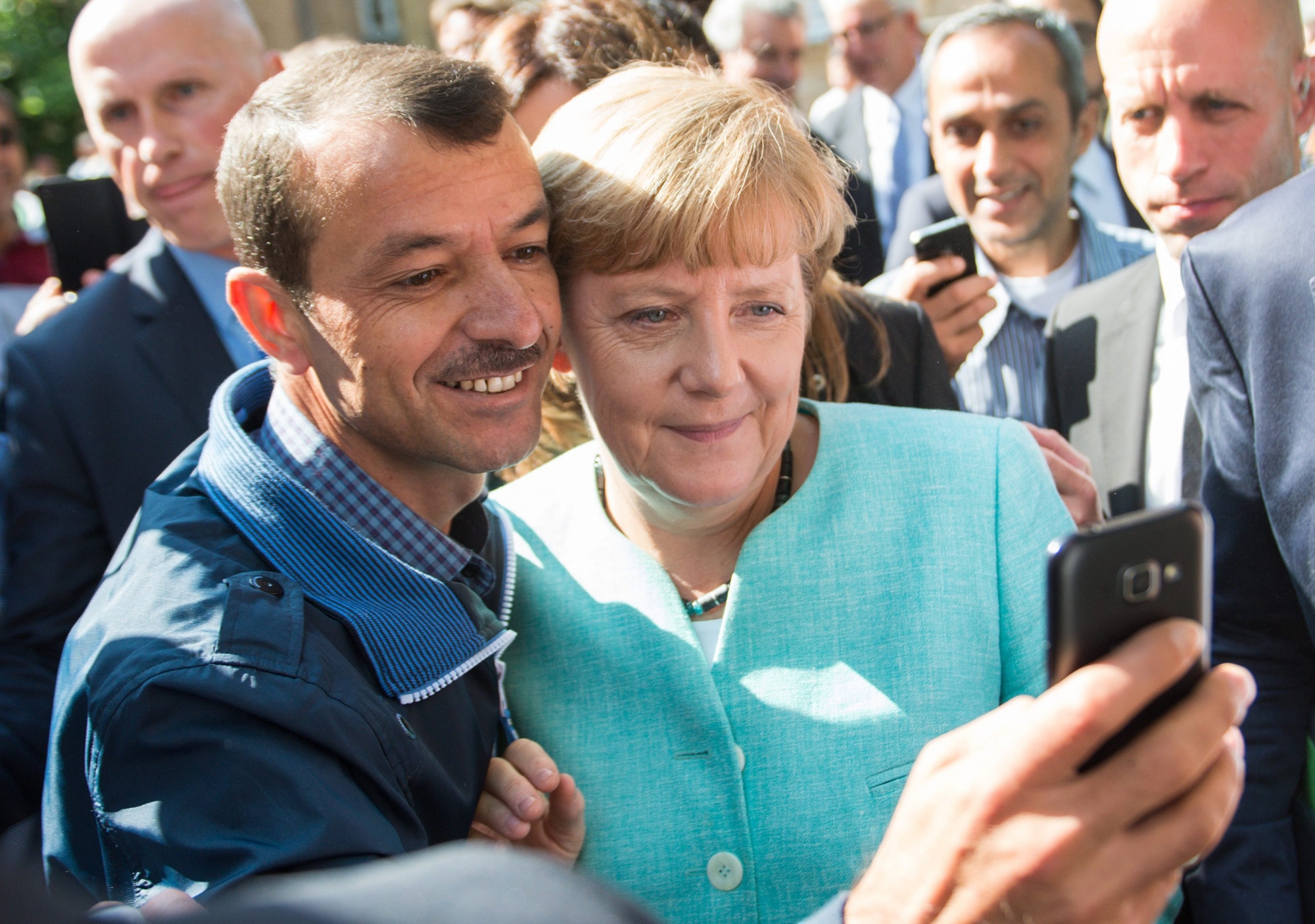 epa04923489 German Chancellor Angela Merkel (R) has a selfie taken with a refugee during a visit to a refugee reception centre in Berlin, Germany, 10 September 2015. Germany can deal with the arrival of hundreds of thousands of refugees without cutting social welfare benefits or raise taxes, Vice Chancellor Sigmar Gabriel said on 10 September, during a debate in parliament on next year's budget. Germany expects 800,000 asylum seekers this year, four times more than last year and more than any other country in the European Union, which is split on how to deal with the biggest refugee crisis since World War II.  EPA/BERND VON JUTRCZENKA DEUTSCHLAND MIGRATION