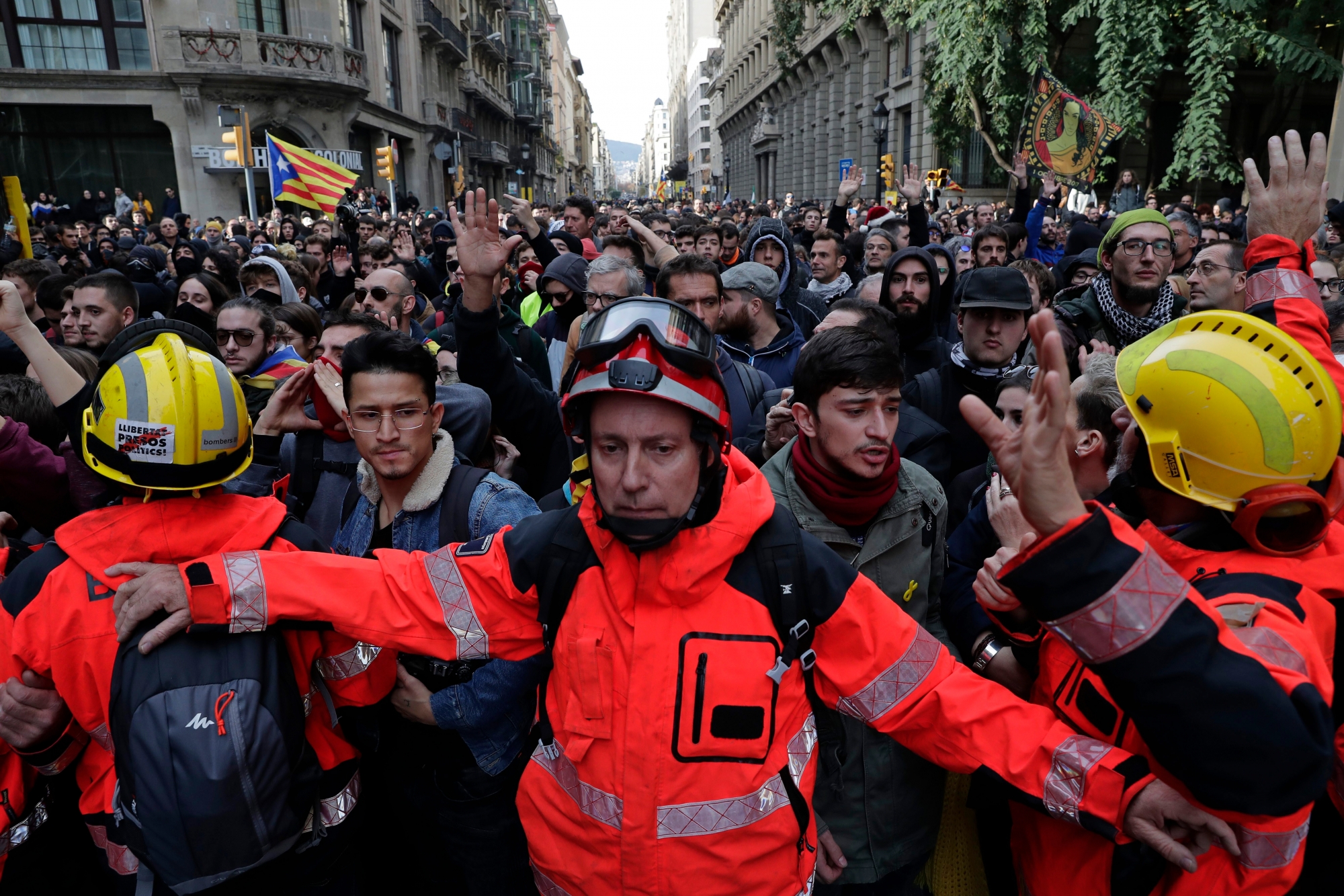 Firefighters help to control the demonstrators during a protest against Spain's cabinet holding a meeting in Barcelona Spain, Friday Dec. 21, 2018. Scuffles broke out between protesters trying to reach the venue of the cabinet meeting and police trying to stop them on Friday in central Barcelona after pro-independence organizations called for peaceful demonstrations against the meeting across the city. (AP Photo/Manu Fernandez) Spain Catalonia