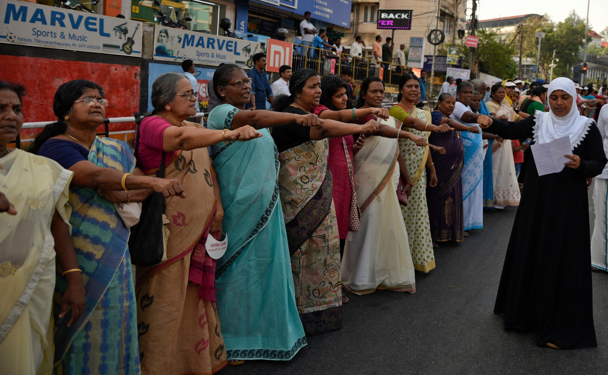 Women raise their hands to take a pledge to fight gender discrimination as they form part of a hundreds kilometer long "women's wall" in Thiruvananthapuram, in the southern Indian state of Kerala, Tuesday, Jan. 1, 2019. The wall was organized in the backdrop of conservative protestors blocking the entry of women of menstruating age at the Sabarimala temple, one of the world's largest Hindu pilgrimage sites defying a recent ruling from India's top court to let them enter. (AP Photo/R.S. Iyer) India Temple Women