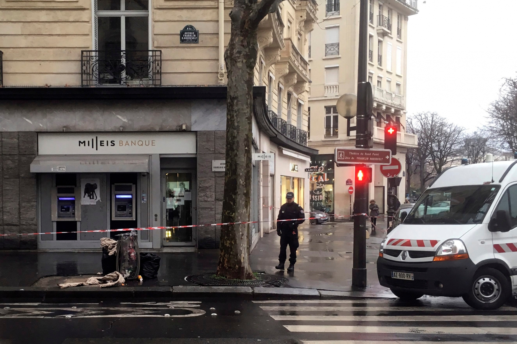 A police officer guards the Milleis bank after a robbery in Paris, Tuesday, Jan.22, 2019. Paris police say several suspects are on the run after they robbed the bank on the Champs-Elysees in broad daylight. (AP Photo/Bertrand Combaldieu) France Bank Robbery