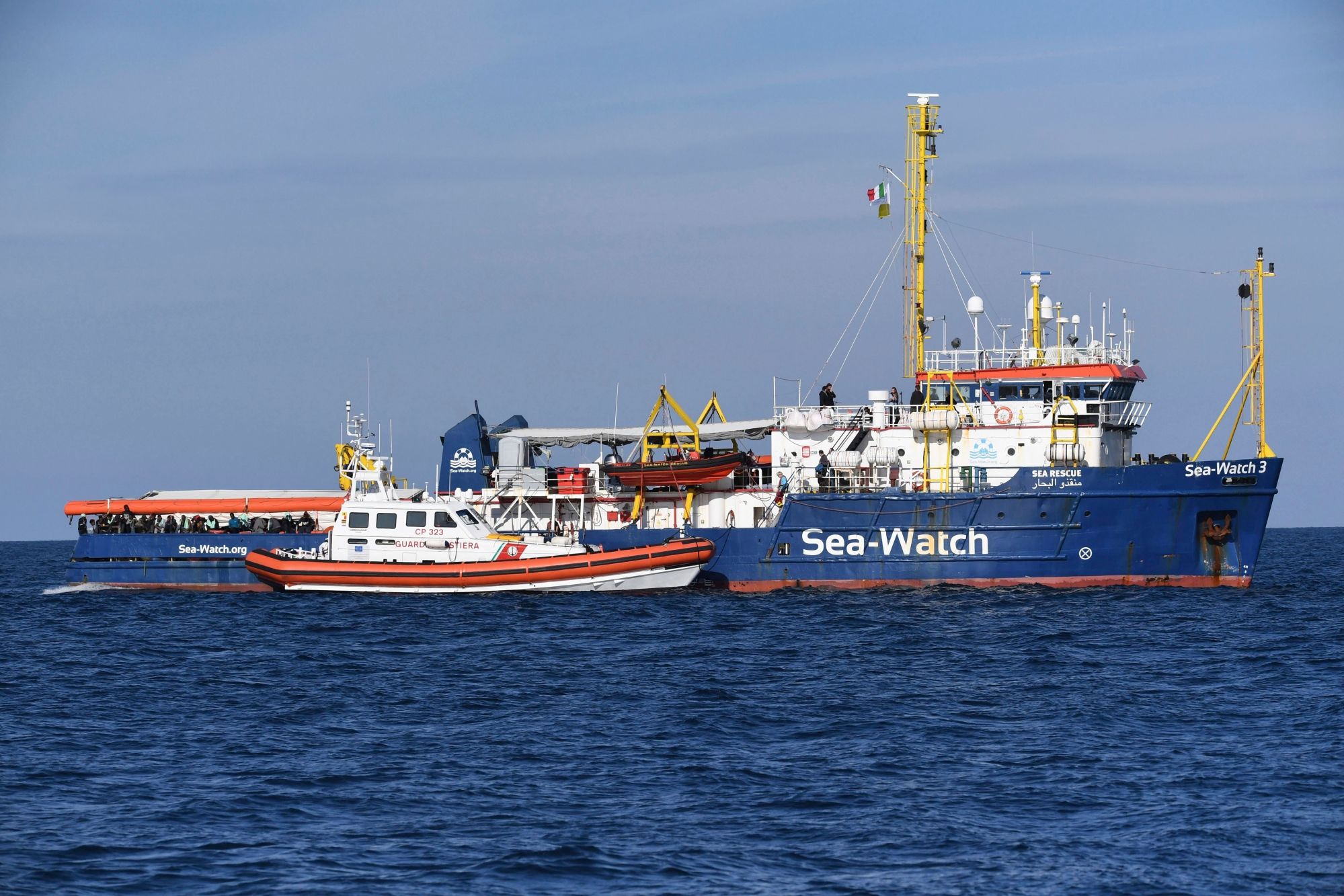 A coastguard boat approaches the German humanitarian group's rescue boat Sea Watch 3, to deliver food and blankets for the cold, off the coast of Syracuse, Italy, Sunday, Jan. 27, 2019. The Italian coast guard is bringing socks, shoes, bread and fruit to 47 migrants who have been stranded at sea for nine days aboard a German ship. (AP Photo/Salvatore Cavalli) Italy Europe Migrants