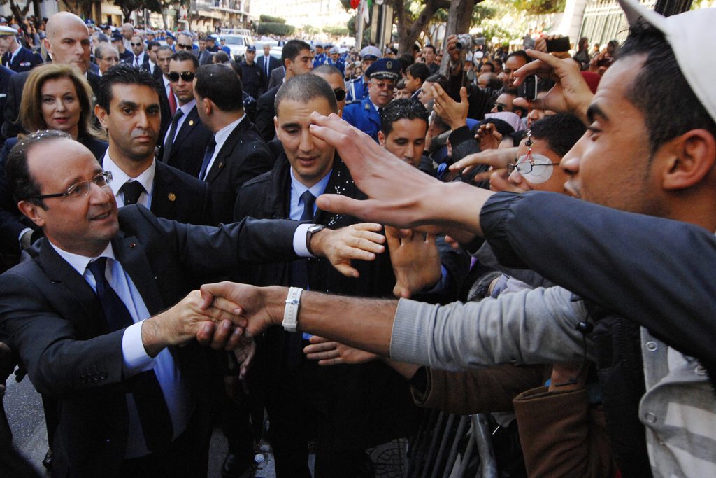 French President Francois Hollande, left, greets Algerians as he walks in Algiers, Thursday, Dec. 20, 2012. French President Francois Hollande acknowledged the "unjust" and "brutal" nature of France's occupation of Algeria for 132 years, but stopped short Thursday of apologizing for the past as many Algerians have demanded. (AP Photo/Sidali Djarboub)