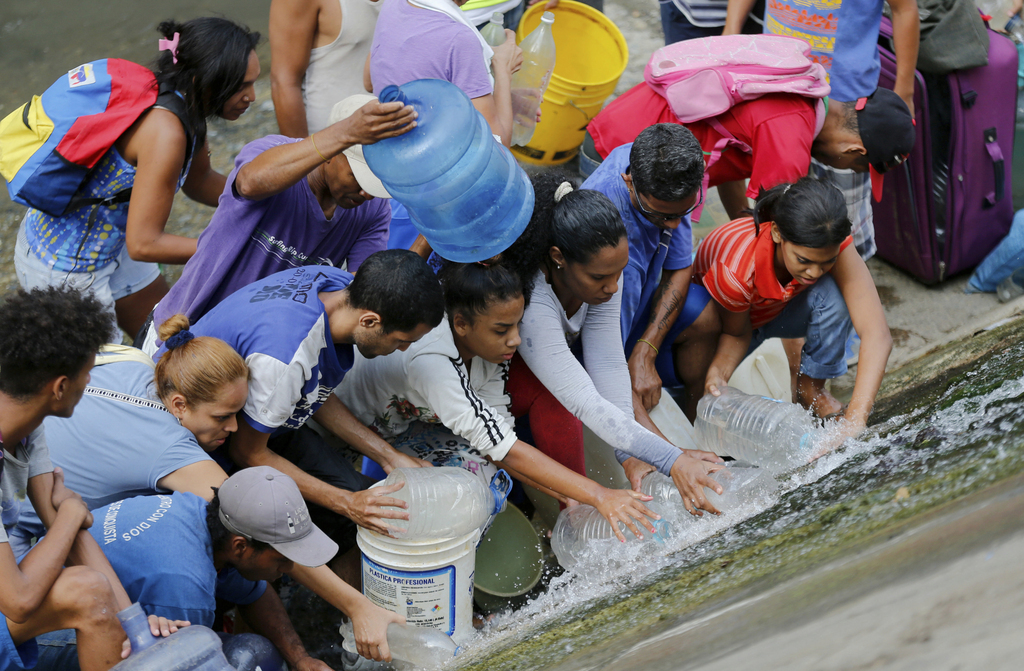 Les habitants de Caracas récupèrent l'eau qui fuit d'une canalisation de la rivière Guaire, l'une des plus polluées du pays.