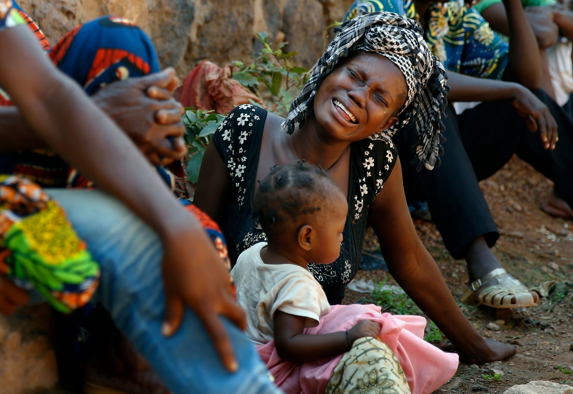 Relatives of Thierry Tresor Zumbeti, who died from bullet wounds to the neck and stomach, grieve outside his home in Bangui, Central African Republic, Saturday, Dec. 7, 2013. Zumbeti was buried beside his house. Christians fearing reprisal attacks from the Muslim ex-rebels who control Central African Republic fled on foot by the thousands Saturday, as others ventured outside for the first in time in days only to bury their dead following the worst violence to wrack the lawless country in months. (AP Photo/Jerome Delay) APTOPIX Central African Republic