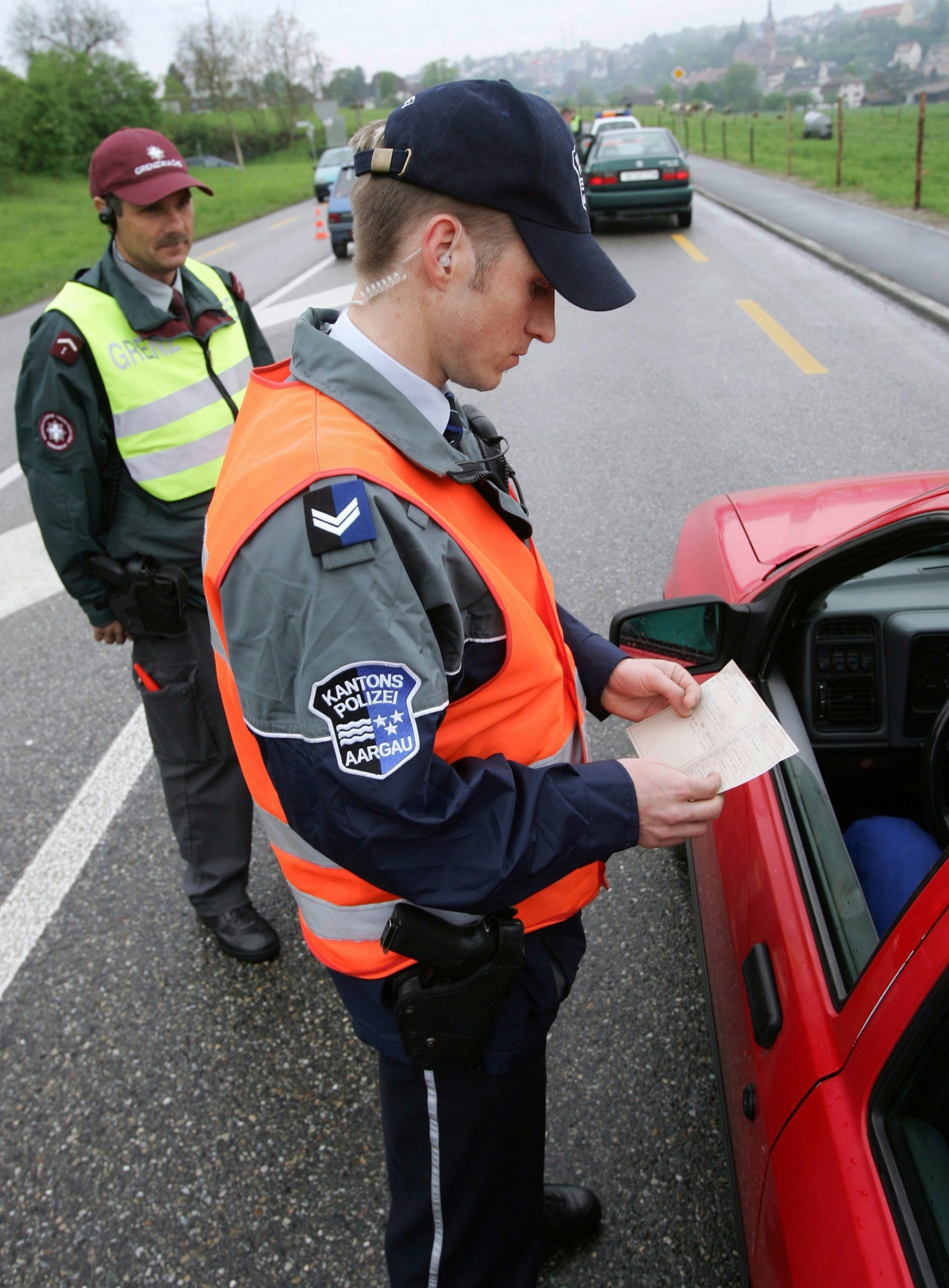 Ein Aargauer Polizist und ein Grenzbeamter kontrollieren in der Naehe der Zollanlage Laufenburg am Dienstag, 3. Mai 2005, ein Fahrzeug. (KEYSTONE/Markus Stuecklin)  SCHWEIZ GRENZE SCHENGEN