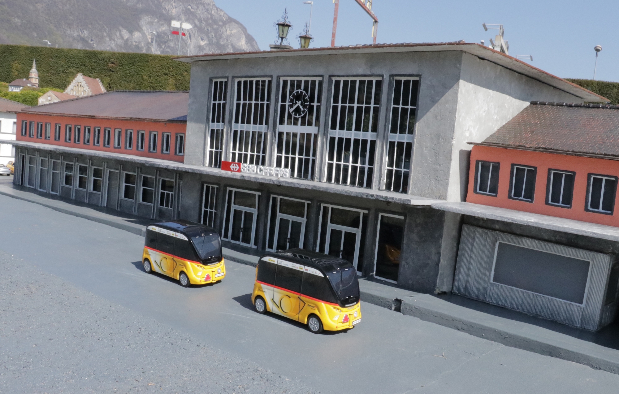 Les deux petites navettes autonomes devant le modèle de la gare de Sion à Swissminiatur.