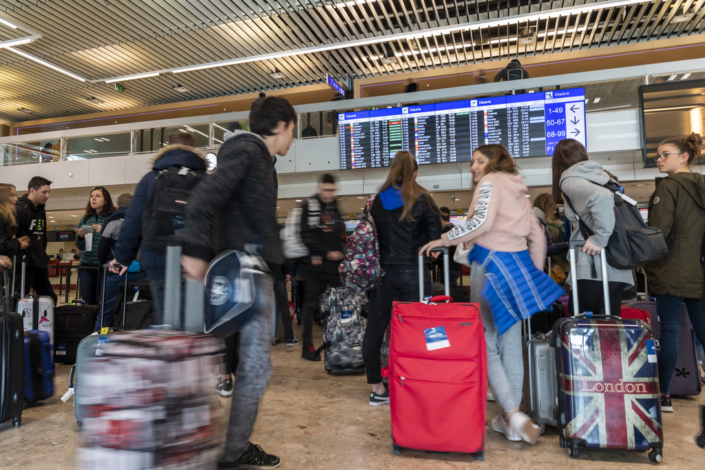 Des passagers attendent avec leurs bagages de prendre l'avion, avant conference de presse de la presentation du rapport annuel 2018 de Geneve Aeroport ainsi que ses projets futurs, ce mercredi 27 mars 2019 a Geneve. (KEYSTONE/Martial Trezzini)