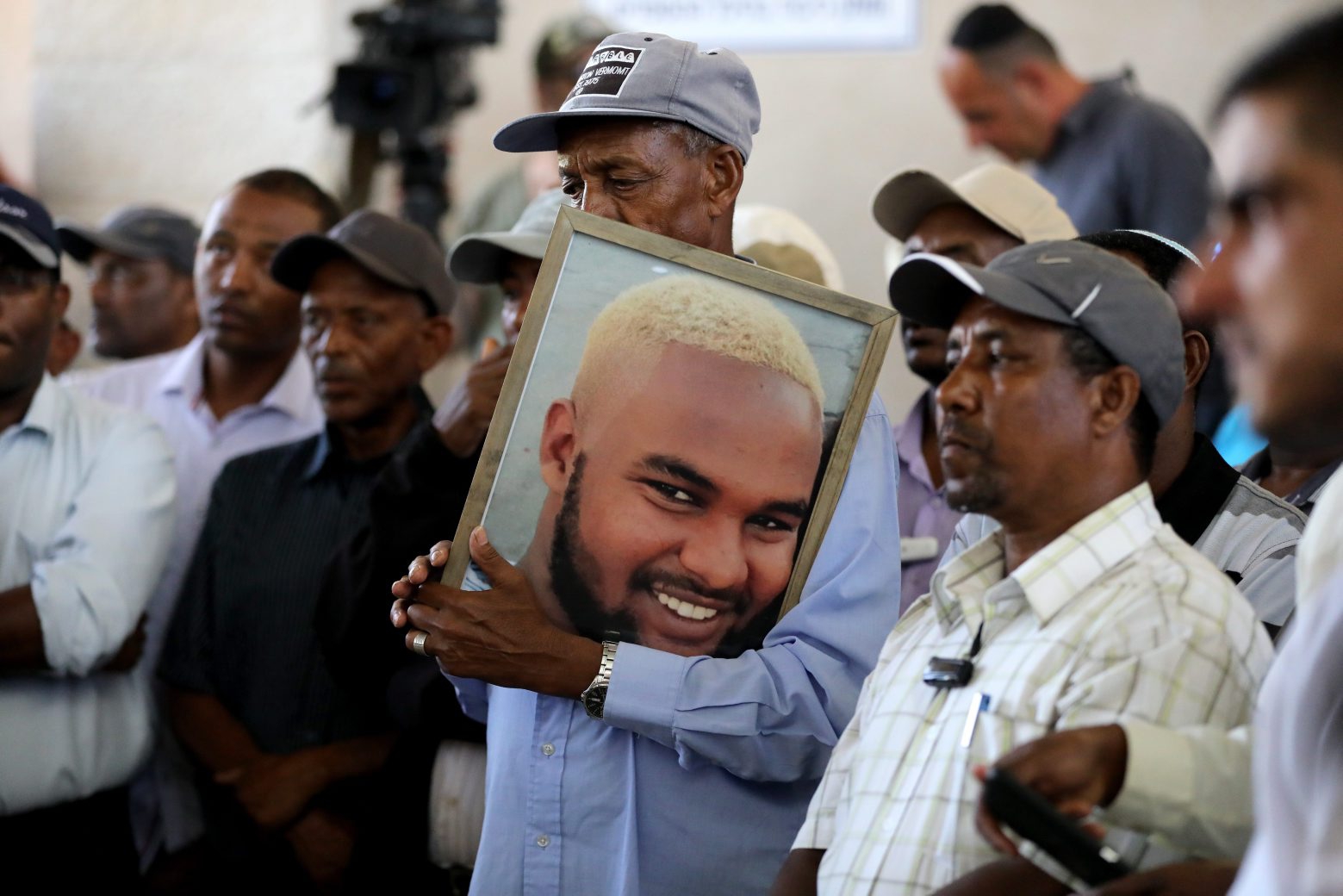 epa07689267 Family members and friends hold a picture and mourn during the funeral of Israeli teen of Ethiopian descent Salamon Taka at the Tel Regev cemetery near Haifa, Israel, 02 July 2019. Reports state the 18-year -old Taka was shot dead on 30 June by an off-duty police officer in Kiryat Haim, a suburb of Haifa. His death sparked a wave of protest throughout the country as thousands of the Ethiopian community blocked roads, shouted slogans and called for equality and a halt of excessive police violence.  EPA/ABIR SULTAN MIDEAST ISRAEL ETHIOPIANS PROTEST