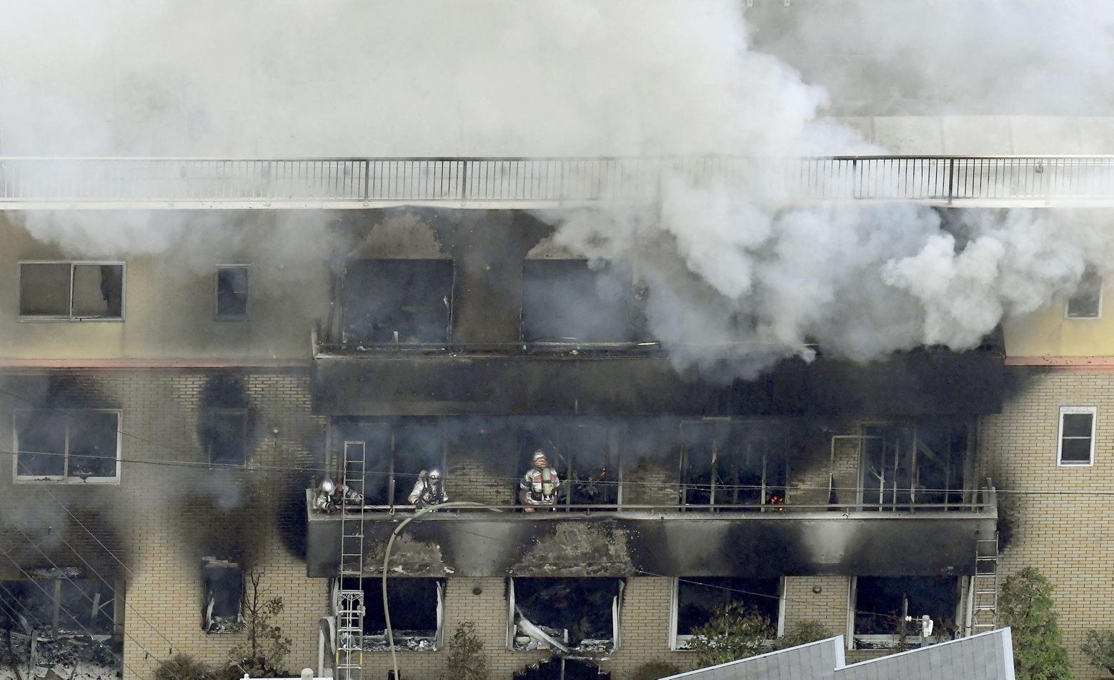 Firefighters work as smoke billows from a three-story building of Kyoto Animation in a fire in Kyoto, western Japan, Thursday, July 18, 2019. Kyoto prefectural police said the fire broke out Thursday morning after a man burst into it and spread unidentified liquid and put fire. (Kyodo News via AP) APTOPIX Japan Animation Studio Fire