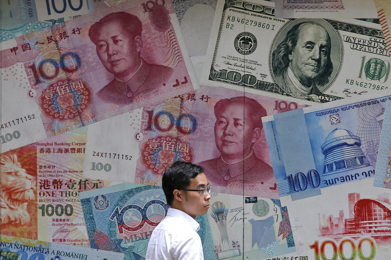 FILE - In this June 10, 2019, file photo, a man walks past a money exchange shop decorated with different banknotes at Central, a business district of Hong Kong. China's yuan fell below the politically sensitive level of seven to the U.S. dollar on Monday, Aug. 5, 2019, possibly adding to trade tension with Washington. The currency weakened to 7.0177 in early trading following U.S. President Donald Trump's threat last week of tariff hikes on additional Chinese imports in a fight over Beijing's trade surplus and technology policies. (AP Photo/Kin Cheung, File) China Sinking Yuan