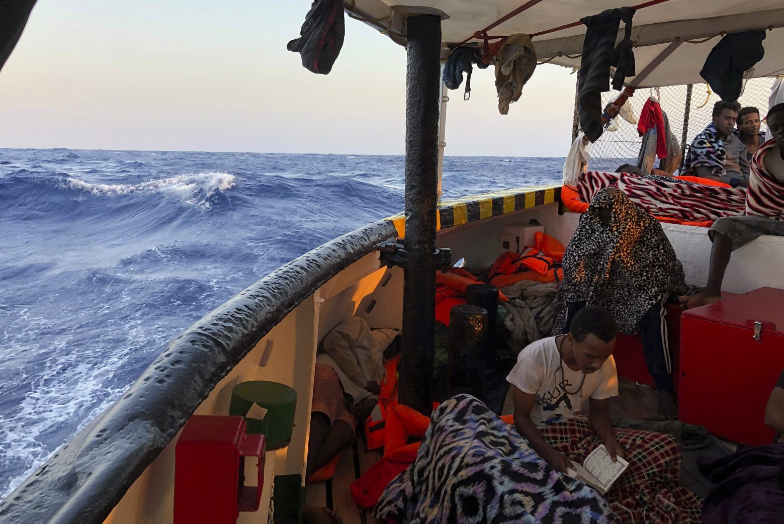 A migrant reads verses of the Quran aboard the Open Arms Spanish humanitarian boat as it arrives near Lampedusa coast in the Mediterranean Sea, Thursday, Aug.15, 2019. A Spanish aid boat with 147 rescued migrants aboard is anchored off a southern Italian island as Italy's ministers spar over their fate. (AP Photo/Francisco Gentico) Europe Migrants
