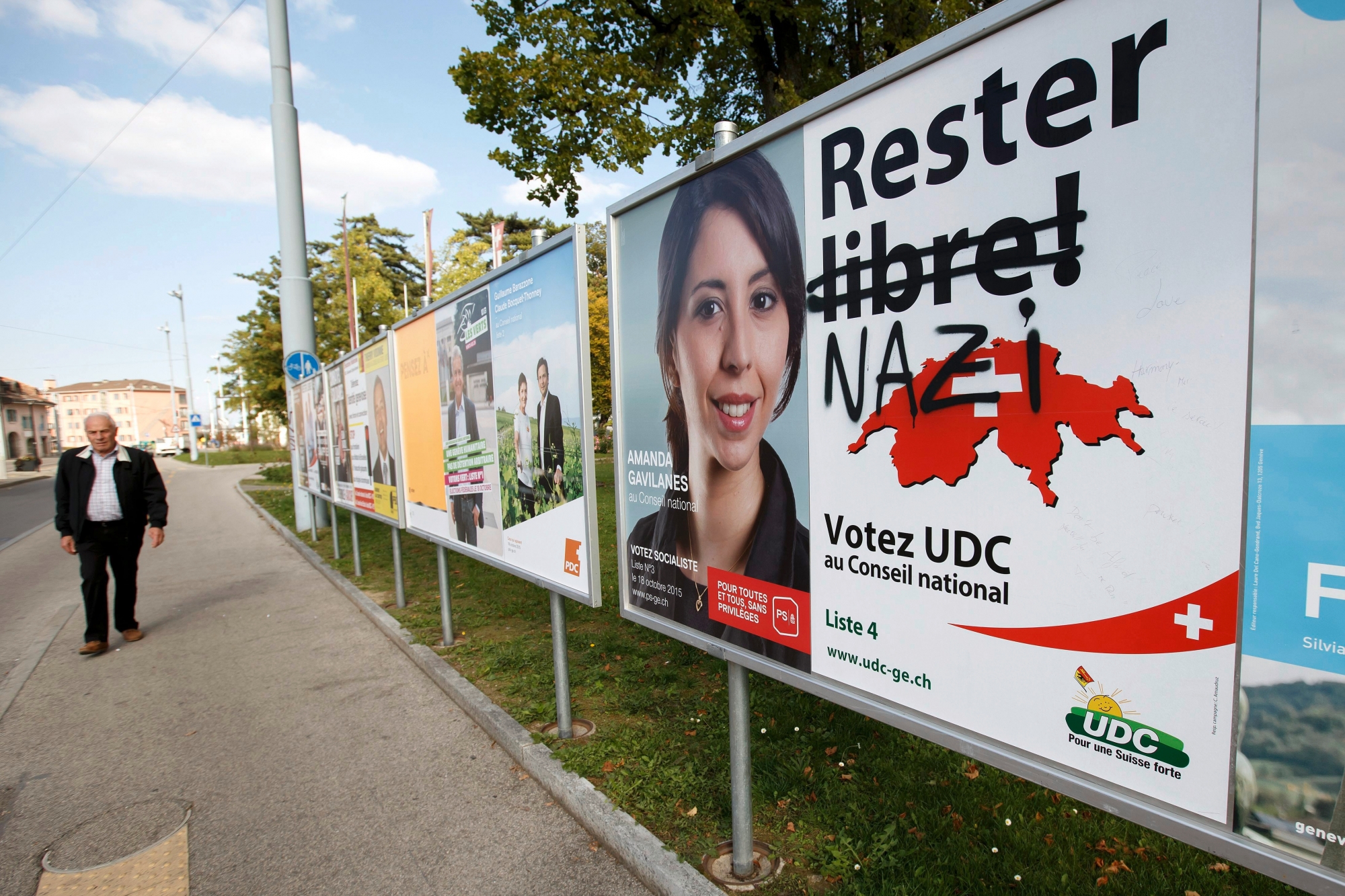 Une personne passe vers les affiches electorales du Parti Socialiste (PS), du Parti liberal-radical (PLR) et de l'affiche caviardee de l'UDC ou l'on peut lire le mot nazi, pour les elections aux chambres Federales 2015, ce lundi 28 septembre 2015 a Geneve. Les elections Federales pour le Conseil National et le Conseil aux Etats auront lieu le dimanche 18 octobre 2015. (KEYSTONE/Salvatore Di Nolfi) SUISSE AFFICHE ELECTIONS FEDERALES