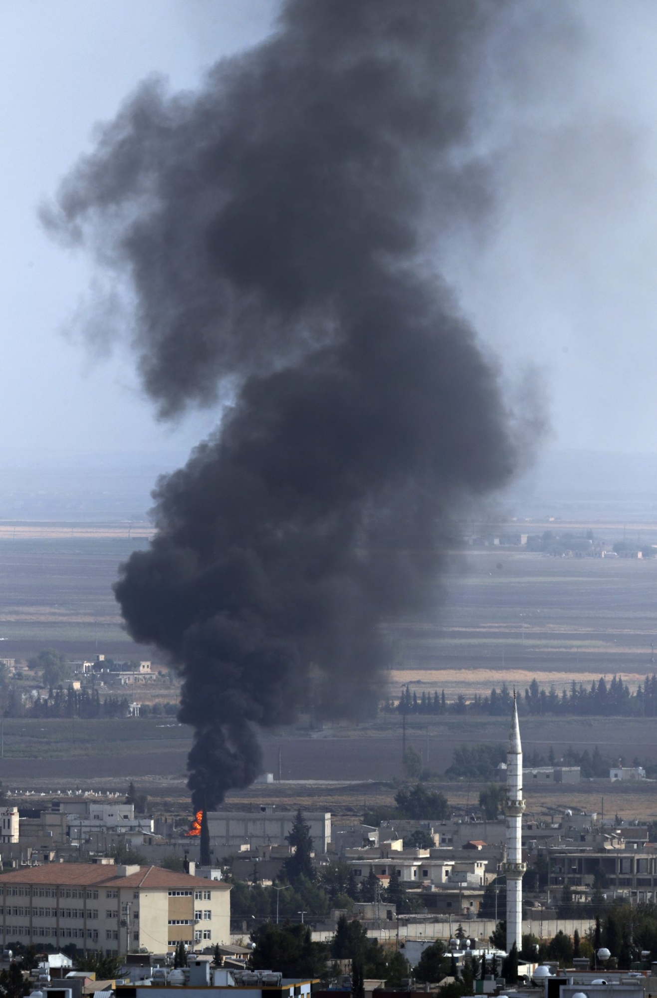 In this photo taken from the Turkish side of the border between Turkey and Syria, in Ceylanpinar, Sanliurfa province, southeastern Turkey, smoke billows from a fire in Ras al-Ayn, Syria, Friday, Oct. 18, 2019. Fighting broke out in the morning hours in the Syrian border town which has been a flashpoint in the fight between Turkey and Kurdish forces despite a U.S.-brokered cease-fire that went into effect overnight. The fighting died down in mid-morning. (AP Photo/Lefteris Pitarakis) Turkey Syria