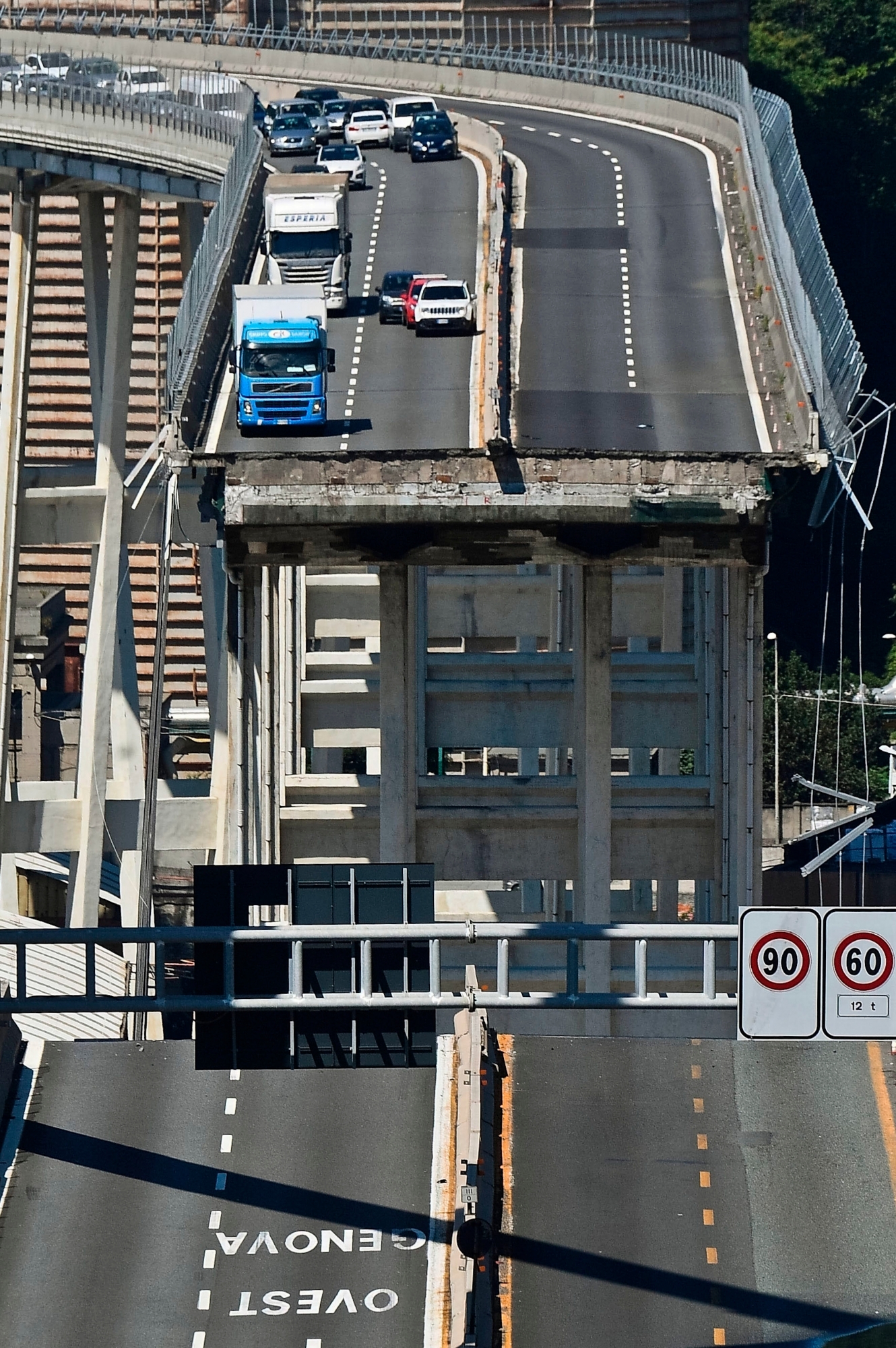 Vehicles are blocked on the collapsed Morandi highway bridge in Genoa, northern Italy, Wednesday, Aug. 15, 2018. A bridge on a main highway linking Italy with France collapsed in the Italian port city of Genoa during a sudden, violent storm, sending vehicles plunging 90 meters (nearly 300 feet) into a heap of rubble below.  (Luca Zennaro/ANSA via AP) Italy Highway Collapse