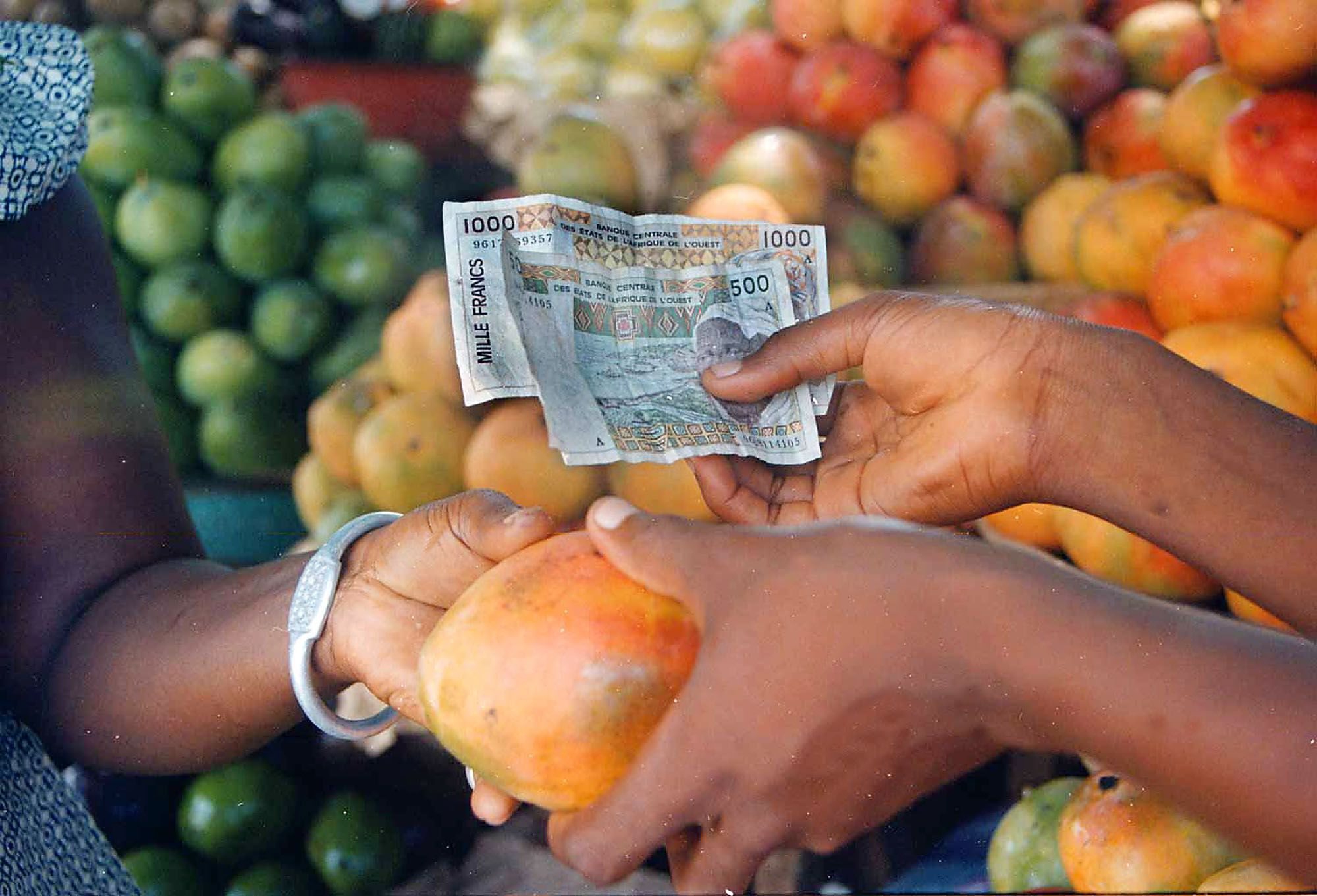 ADVANCE PLEASE HOLD A shopper in Abidjan, Ivory Coast pays for mangoes April 21, 1998 with CFA francs, the France-backed currency used in 15 African countries. Ordinary Africans and analysts alike have speculated that the CFA will be devalued after the introduction of a common European monetary unit in 1999. A CFA devaluation in 1994 sparked a period of social instability that many small traders have yet to recover from. AP photo / Clement Ntaye. ADV EURO MONEY JITTERS